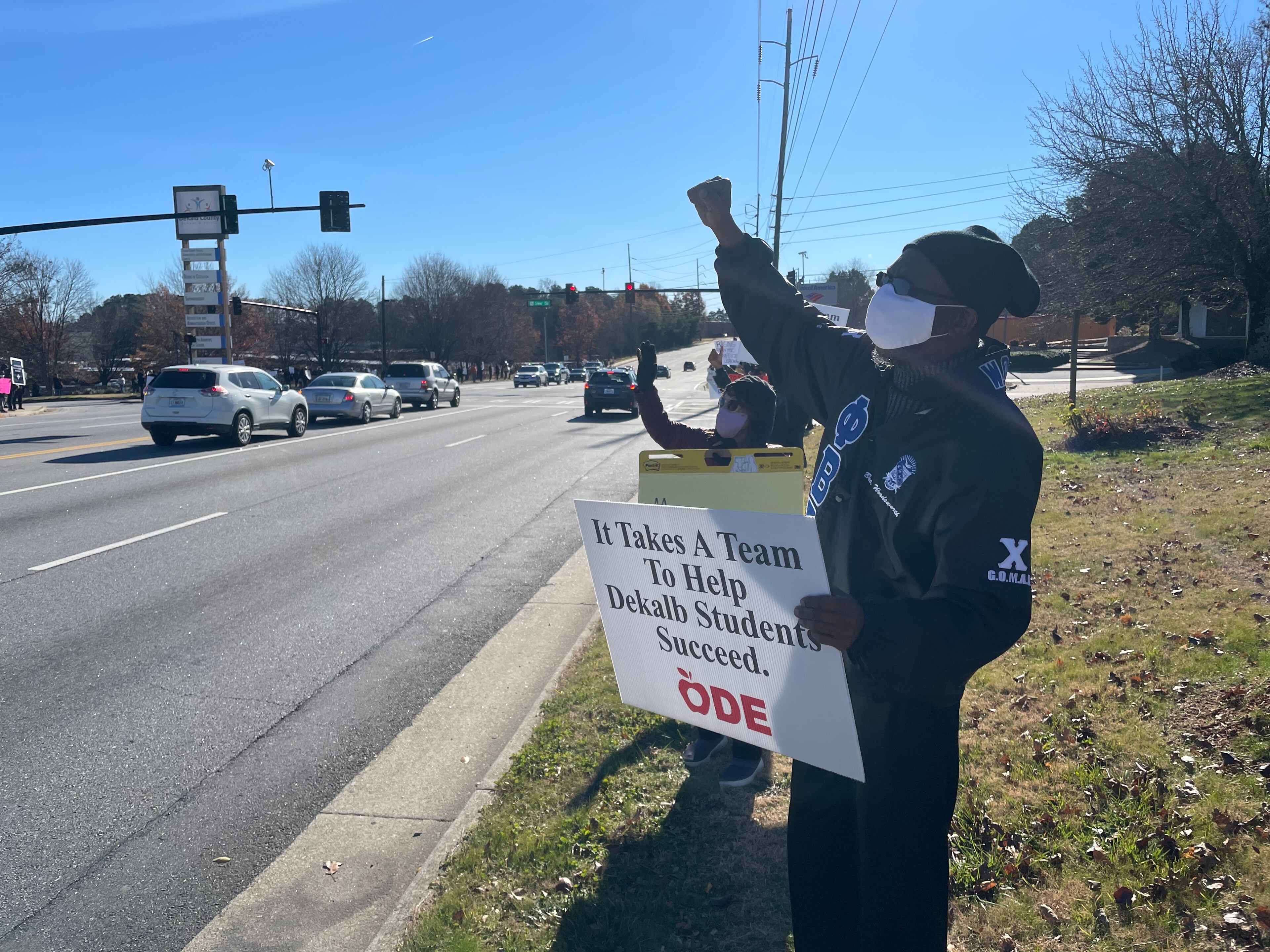 Community members in DeKalb held signs on Tuesday to protest against the reopening of DeKalb County schools.