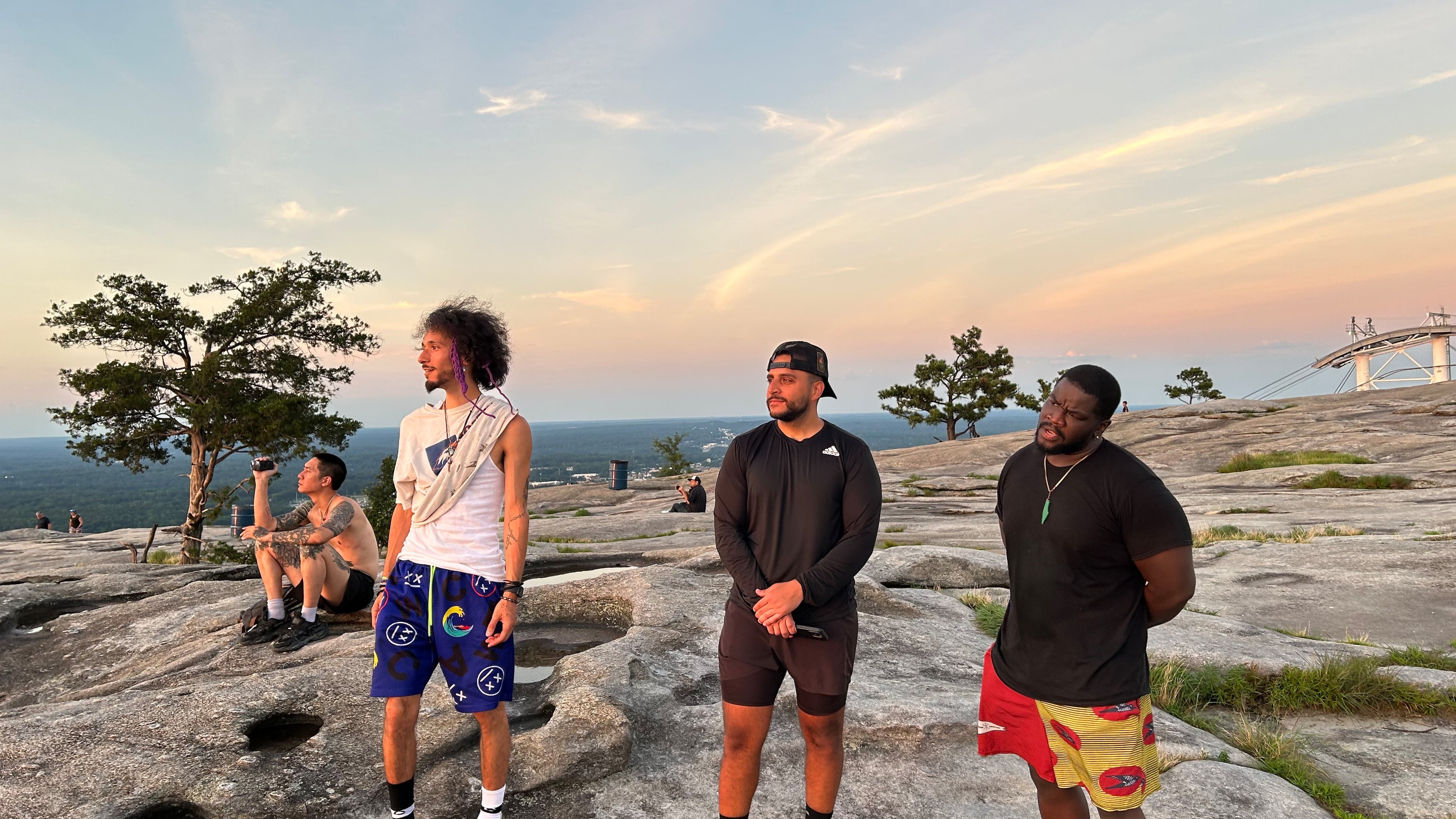 Friends (l-r) Isaiah Ramirez, Faris Mousa and Kelechi Emeonye take in the sunset atop Stone Mountain on Friday June 20, 2025.