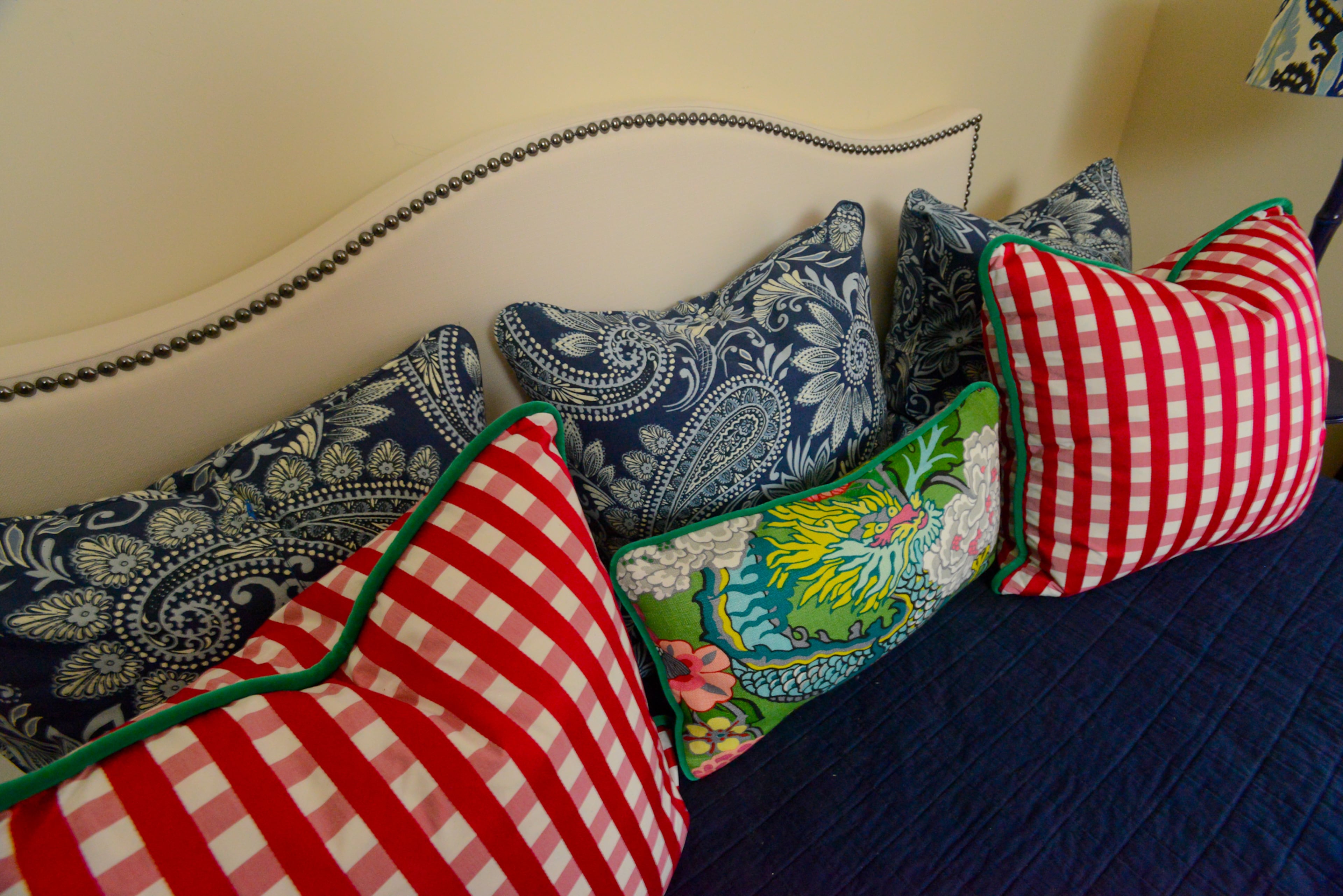 Nailhead trim accents a custom upholstered daybed covered with pillows in buffalo check and other fun prints. Bright colors like tangerine, blue and kelly green fit the home's "Southern preppy" style.