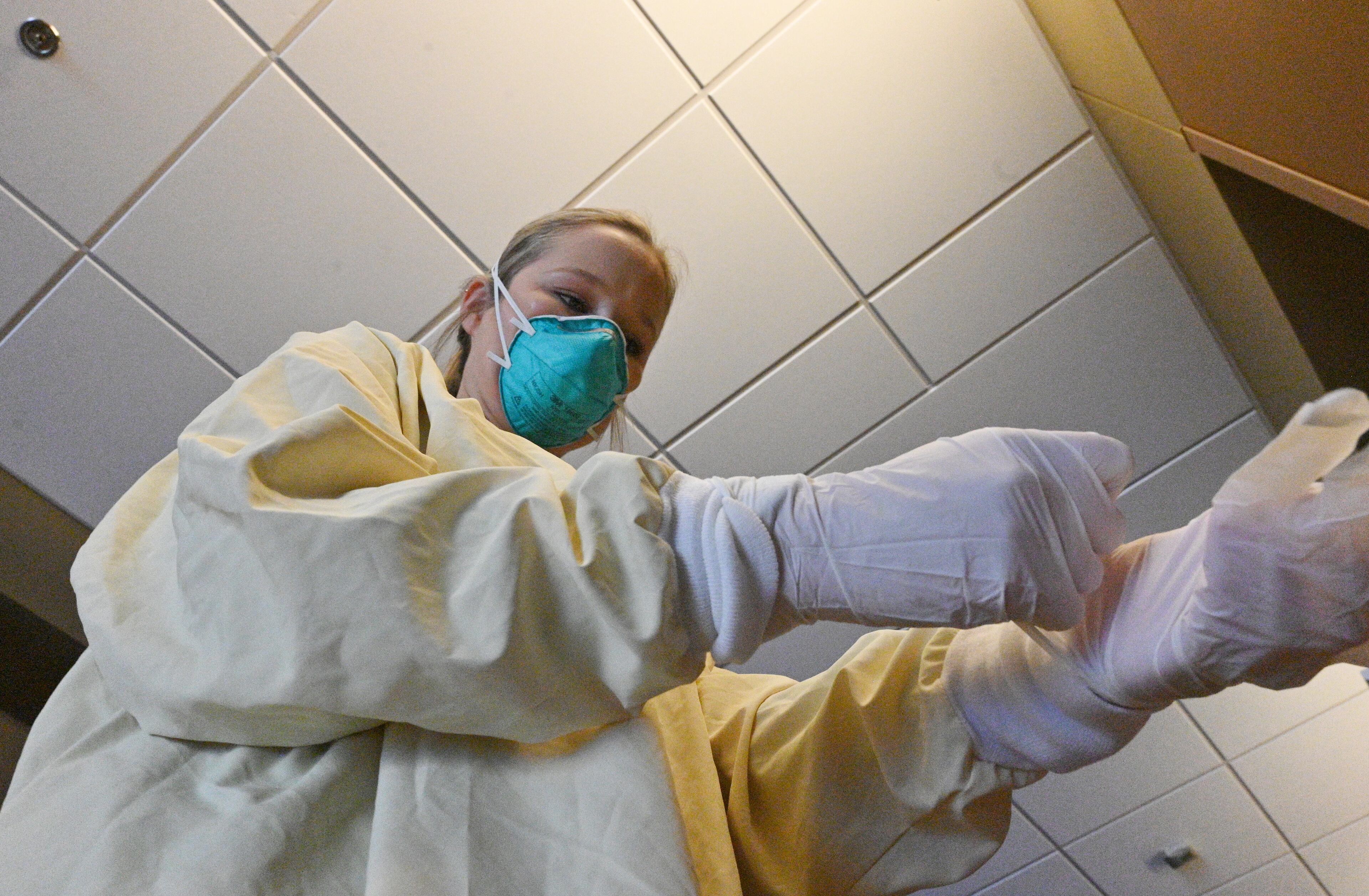 Registered nurse Jordan Davis puts on PPE before she enters to see her patient at the Intensive Care Unit. Davis calls her mom, a nurse of 35 years, on her way home after every shift. Her mom helps her decompress. "And then I go home to my husband, my cat.... You have days you want to cry, you have days you want to scream but knowing you have this knowledge and you have this amount of purpose in someone's life and being able to be there for someone when they are their vulnerable state especially in the ICU. I think that's really important for the patient and the family and our whole team. We play a big part in these patients' lives." (Hyosub Shin / Hyosub.Shin@ajc.com)
