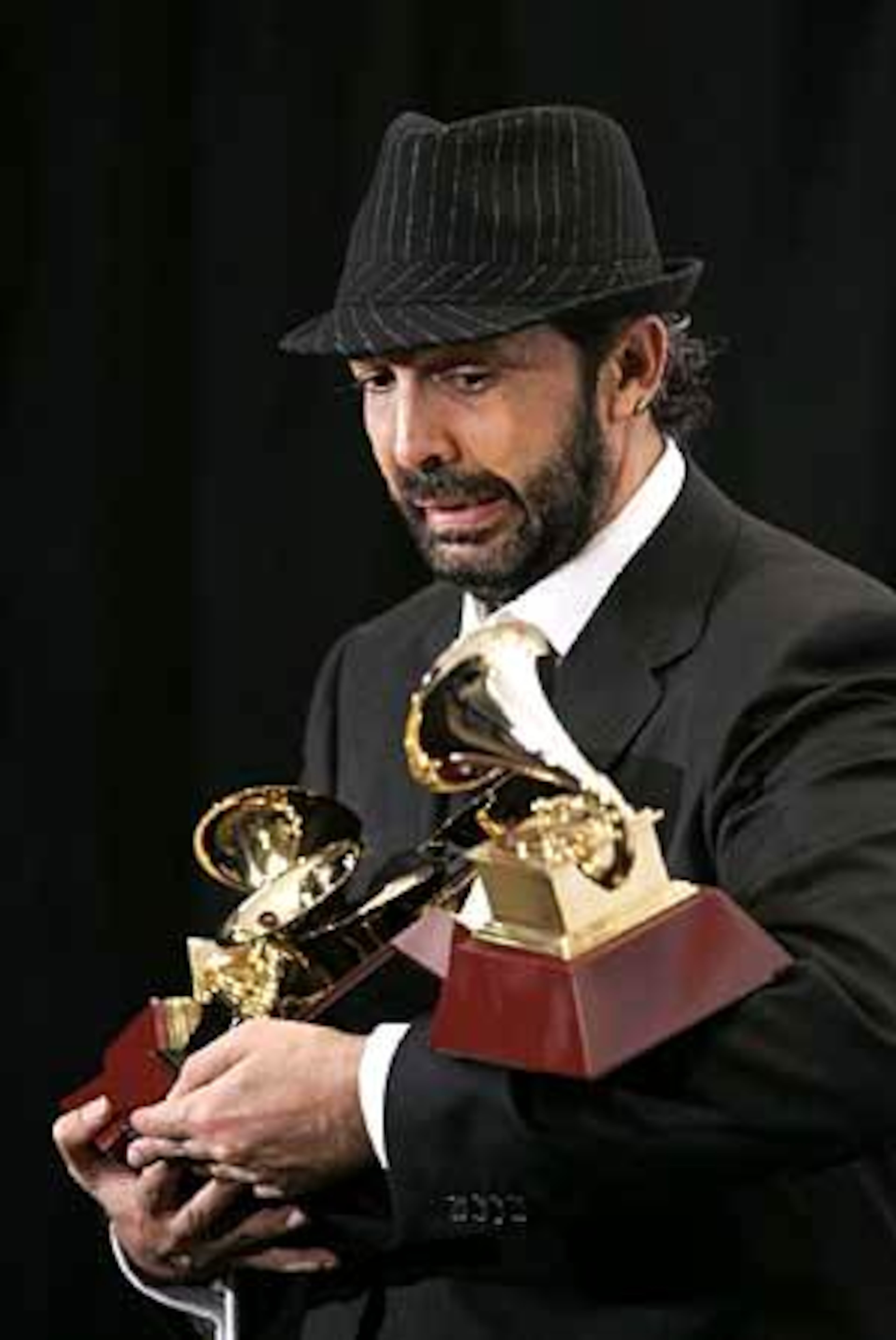 Singer-songwriter Juan Luis Guerra reacts as one of his five Grammy awards falls while he poses backstage. He was a big winner at the event.