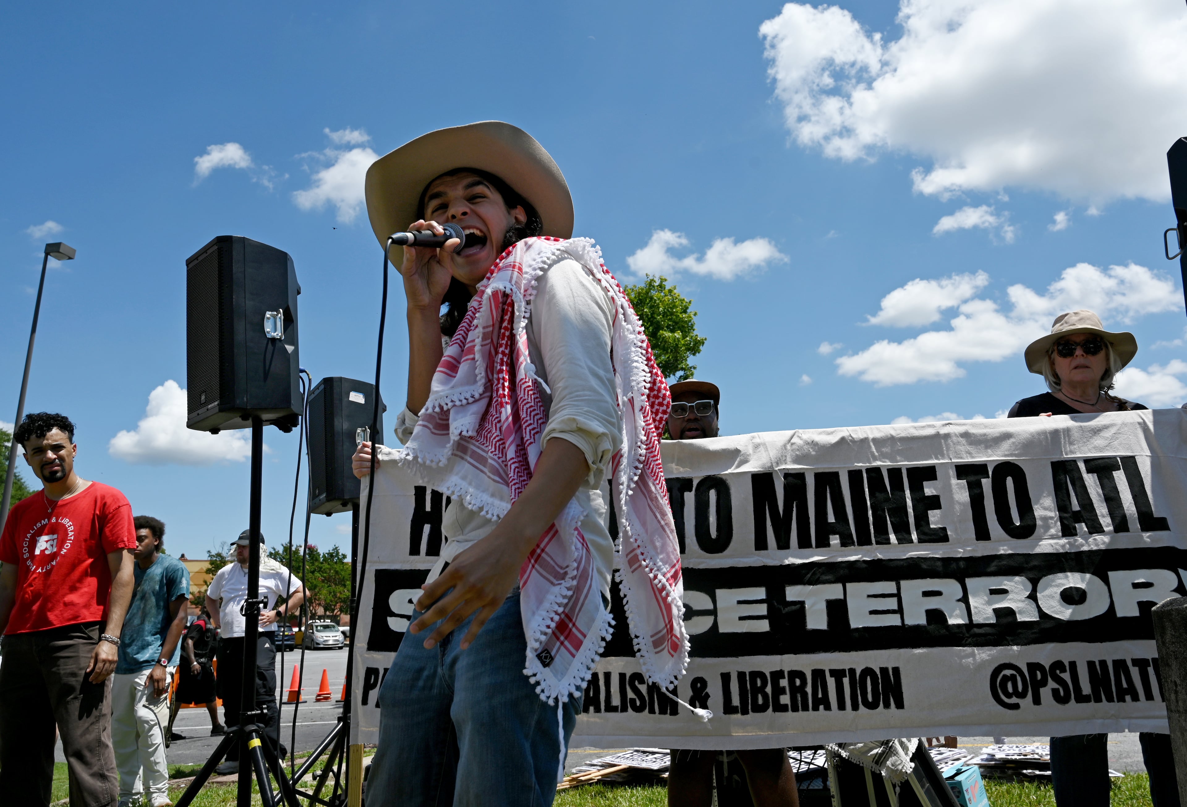Angel Cordova speaks as demonstrators chant while holding signs at the corner of Buford Highway and Briarwood Road to protest recent ICE raids as part of a nationwide Day of Action on Saturday, July 18, 2026, in Atlanta. (Hyosub Shin/AJC)