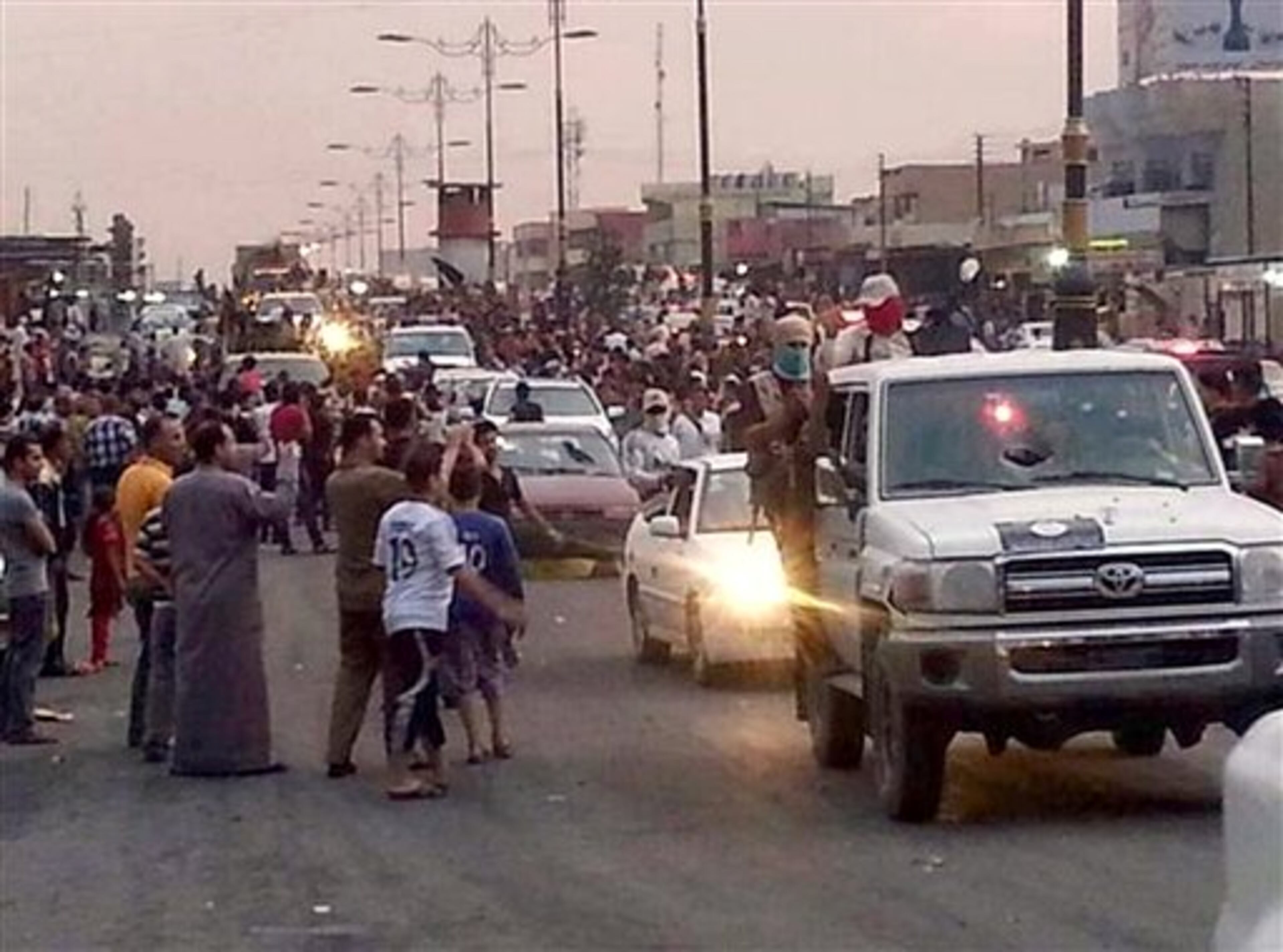 In this still image posted on a militant Twitter account on Wednesday, June 11, 2014, which has been authenticated based on its contents and other AP reporting, militants parade down a main road in Mosul, Iraq. Iraqi officials say al-Qaida-inspired militants who this week seized much of the country's Sunni heartland have pushed into an ethnically mixed province northeast of Baghdad, capturing two towns there.(AP Photo/militant source via Twitter)