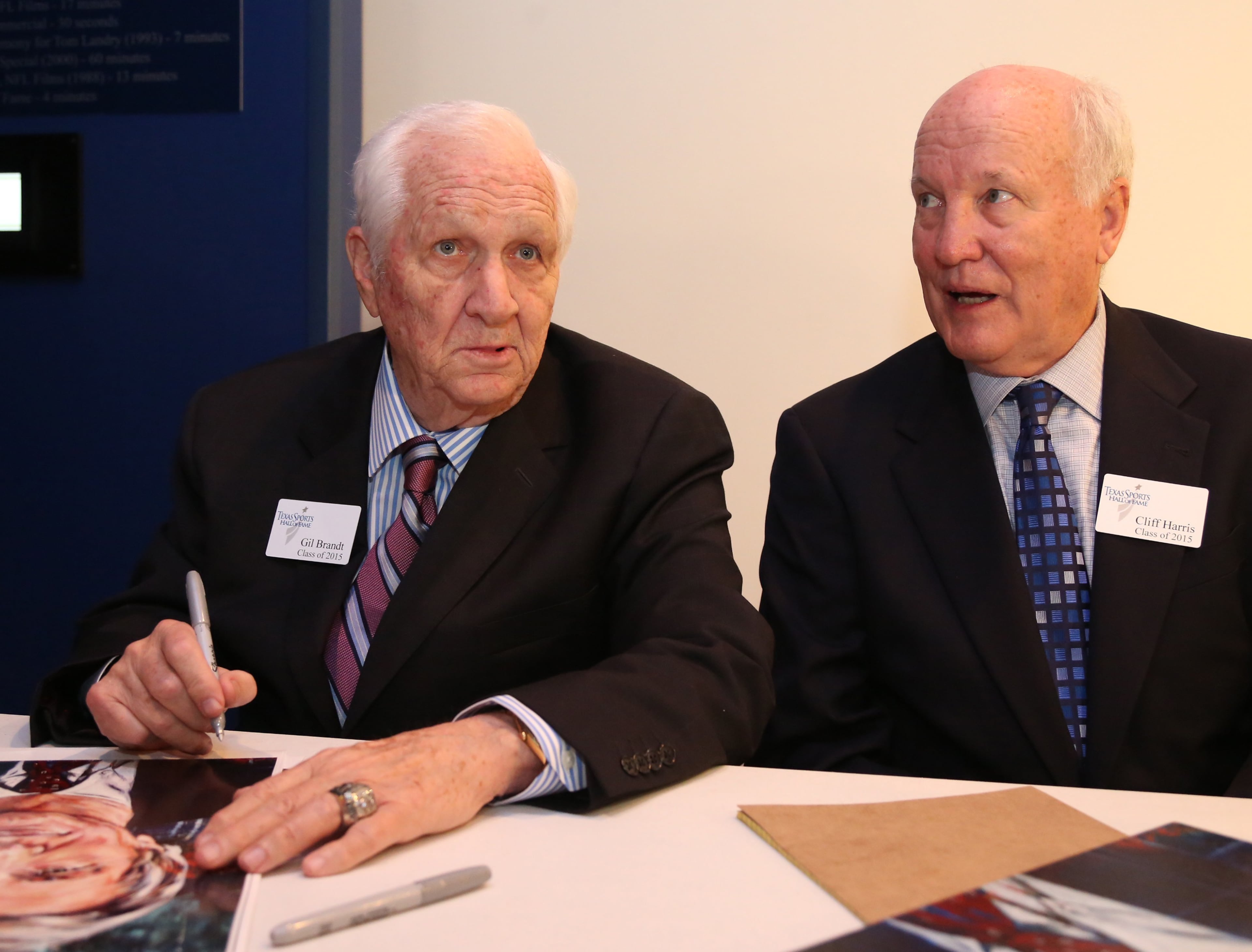 Gil Brandt, left, former Dallas Cowboys vice president of player personnel, signs autographs with former Cowboys defensive back Cliff Harris during the 2015 Texas Sports Hall of Fame induction class news conference, Thursday, April 9, 2015, in Waco, Texas. (AP Photo/Waco Tribune Herald, Rod Aydelotte)