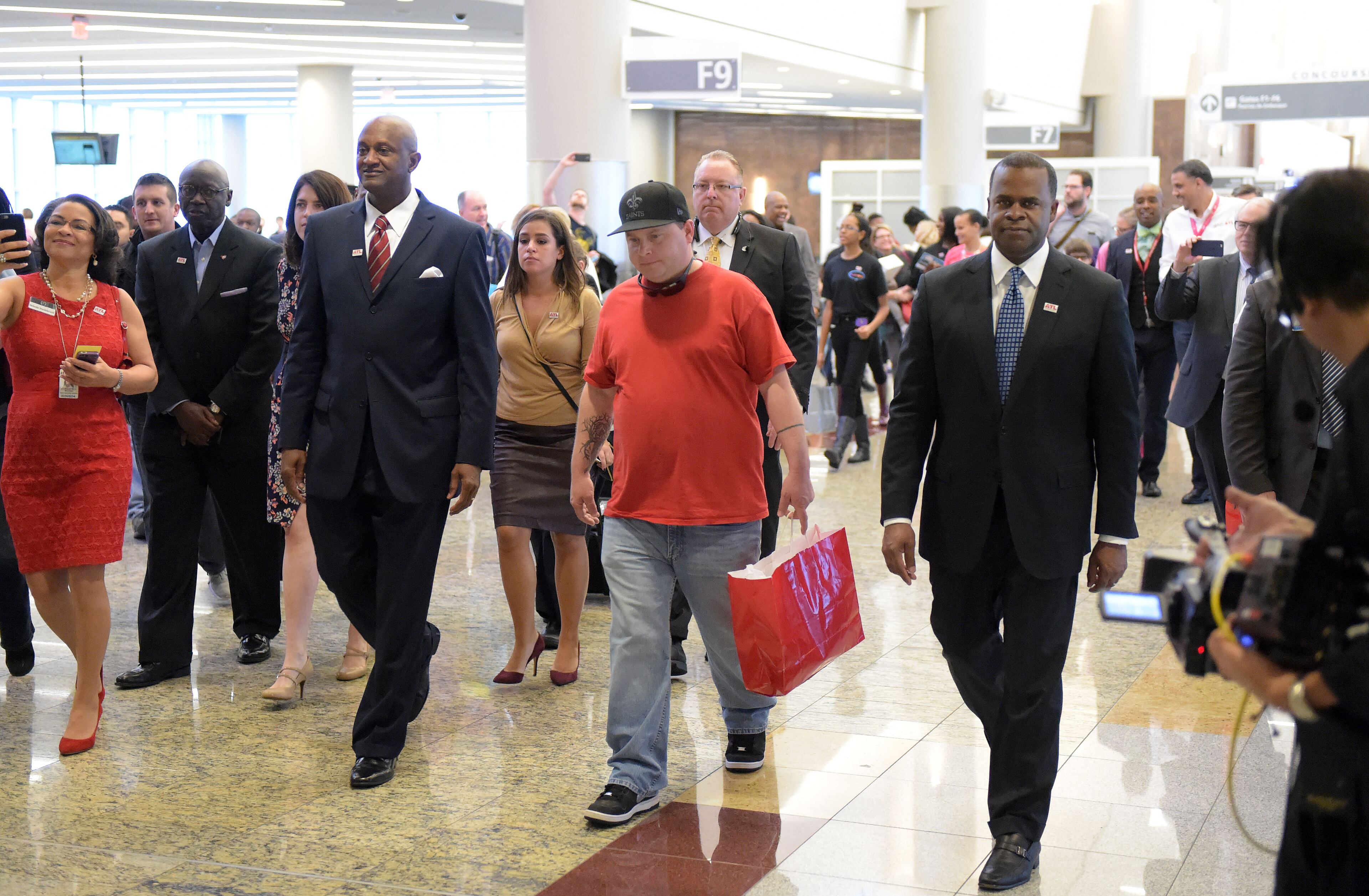 Airport manager Miguel Southwell, passenger Larry Kendrick and Atlanta Mayor Kasim Reed walk through the International terminal following the ceremony. Hartsfield-Jackson International Airport awarded its 100 millionth passenger for 2015 with prizes including a new car, two free airline tickets and a small crowd of officials and television cameras early Sunday December 27, 2015. The Atlanta airport, "the world's busiest" is the first airport in the world to handle 100 million passengers in a year. "It's our commitment that we maintain our position as the world's most traveled airport," said Atlanta Mayor Kasim Reed during remarks at the airport before the flight arrived Sunday morning. The winner, a man from Biloxi named Larry Kendrick who arrived at the airport in blue jeans, an orange t-shirt and a baseball cap, was surprised to learn upon landing that he had been selected as the 100 millionth passenger. KENT D. JOHNSON/ kdjohnson@ajc.com