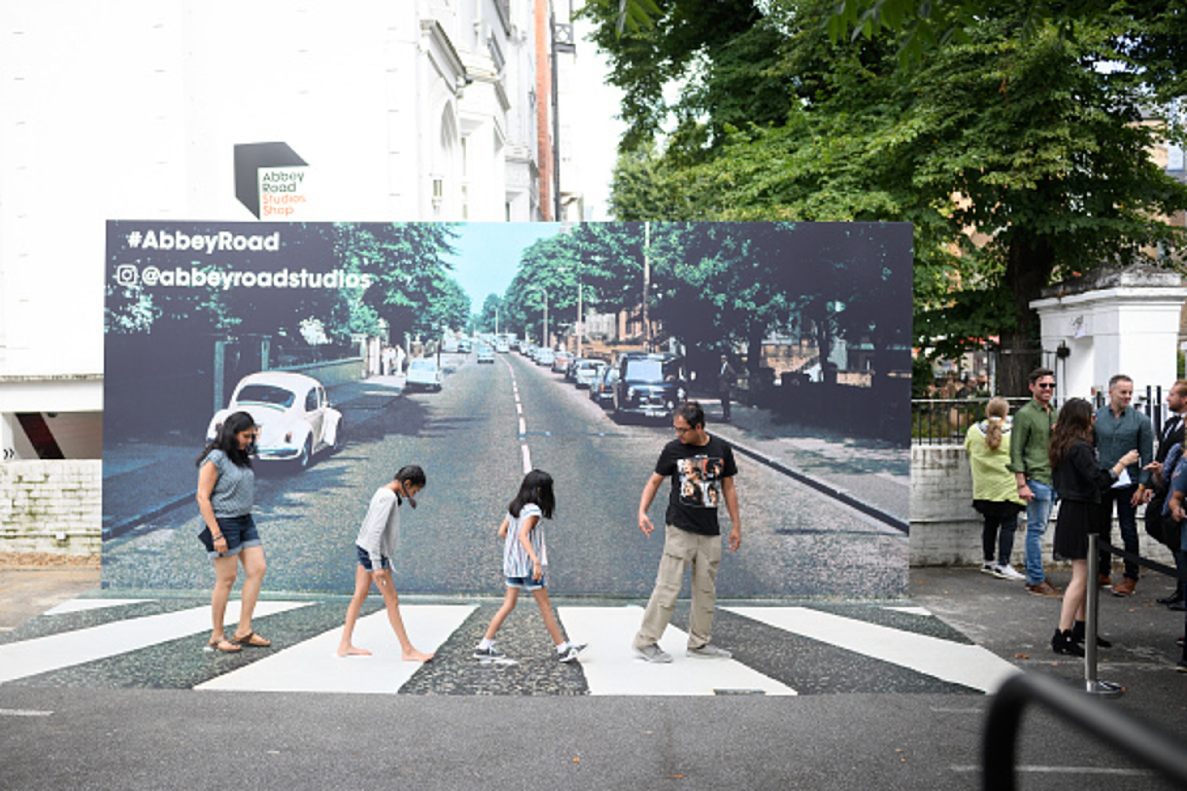 LONDON, ENGLAND - AUGUST 08: Fans pose against a recreation of the pedestrian crossing outside Abbey Road studios, fifty years since the iconic album cover for "Abbey Road" by the Beatles was taken, on August 08, 2019 in London, England. The zebra crossing is just outside the recording studios and has become a popular location for music fans visiting London. (Photo by Leon Neal/Getty Images)