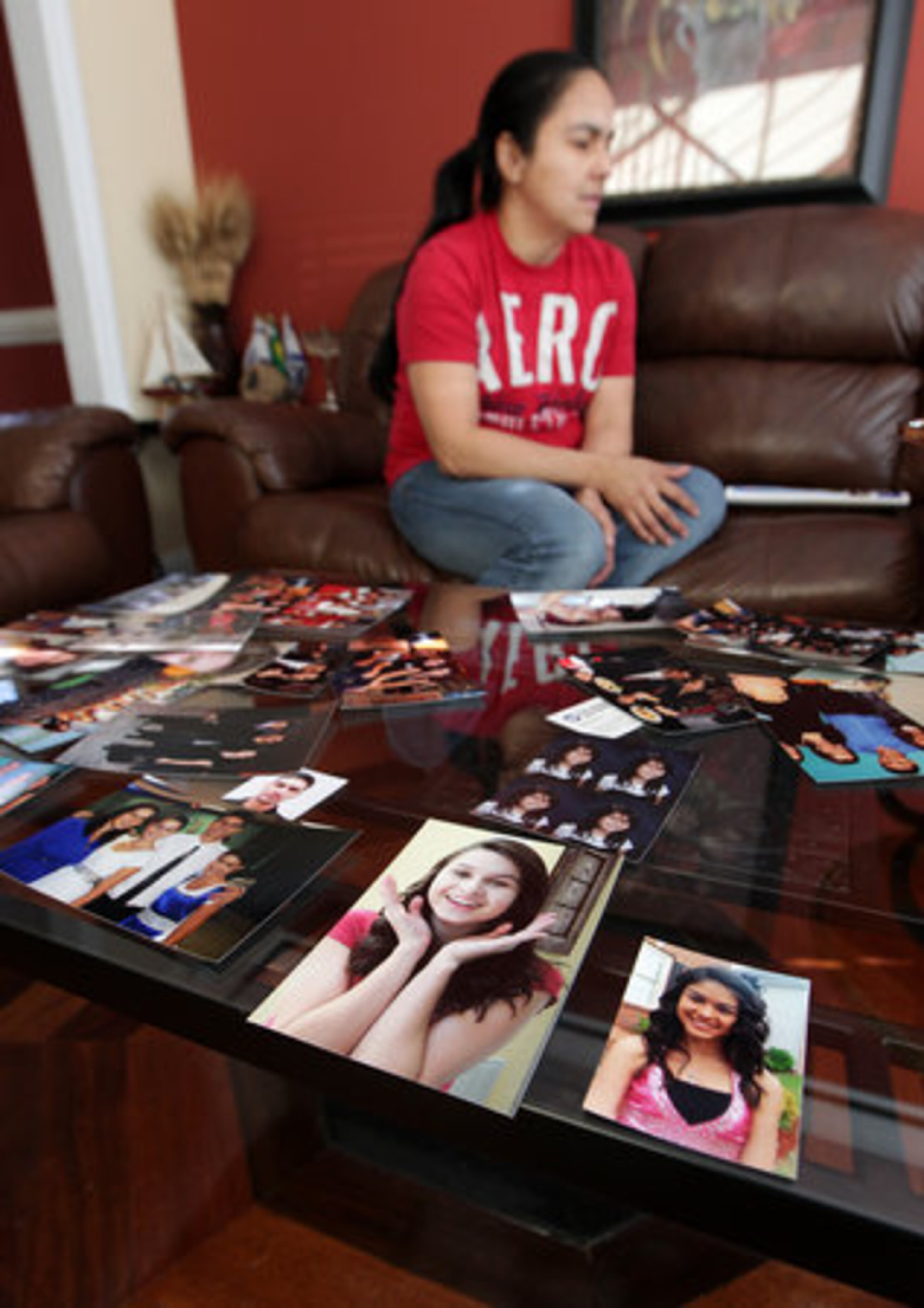 Church member Rosana Alves sits next to dozens of Carmo family photos in the den of the Carmo family home in Kennesaw while receiving well wishers for the family.