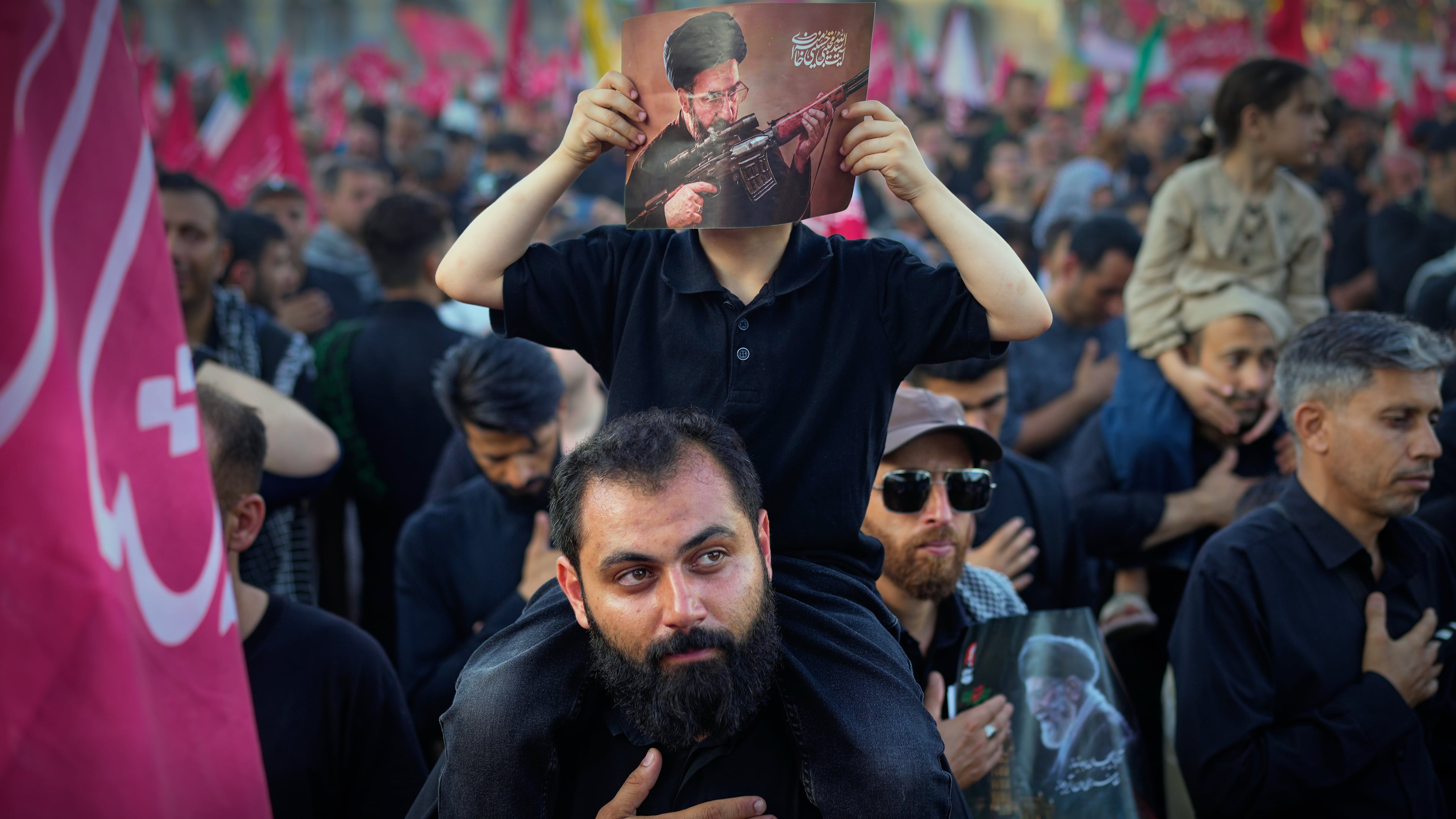 A boy holds a picture of Iran's new Supreme Leader, Mojtaba Khamenei, holding a machine gun at the Imam Khomeini Mosalla Grand Mosque during funeral ceremonies for the slain Iranian Supreme Leader Ayatollah Ali Khamenei and members of his family in Tehran, Iran, Sunday, July 5, 2026. (AP Photo/Altaf Qadri)