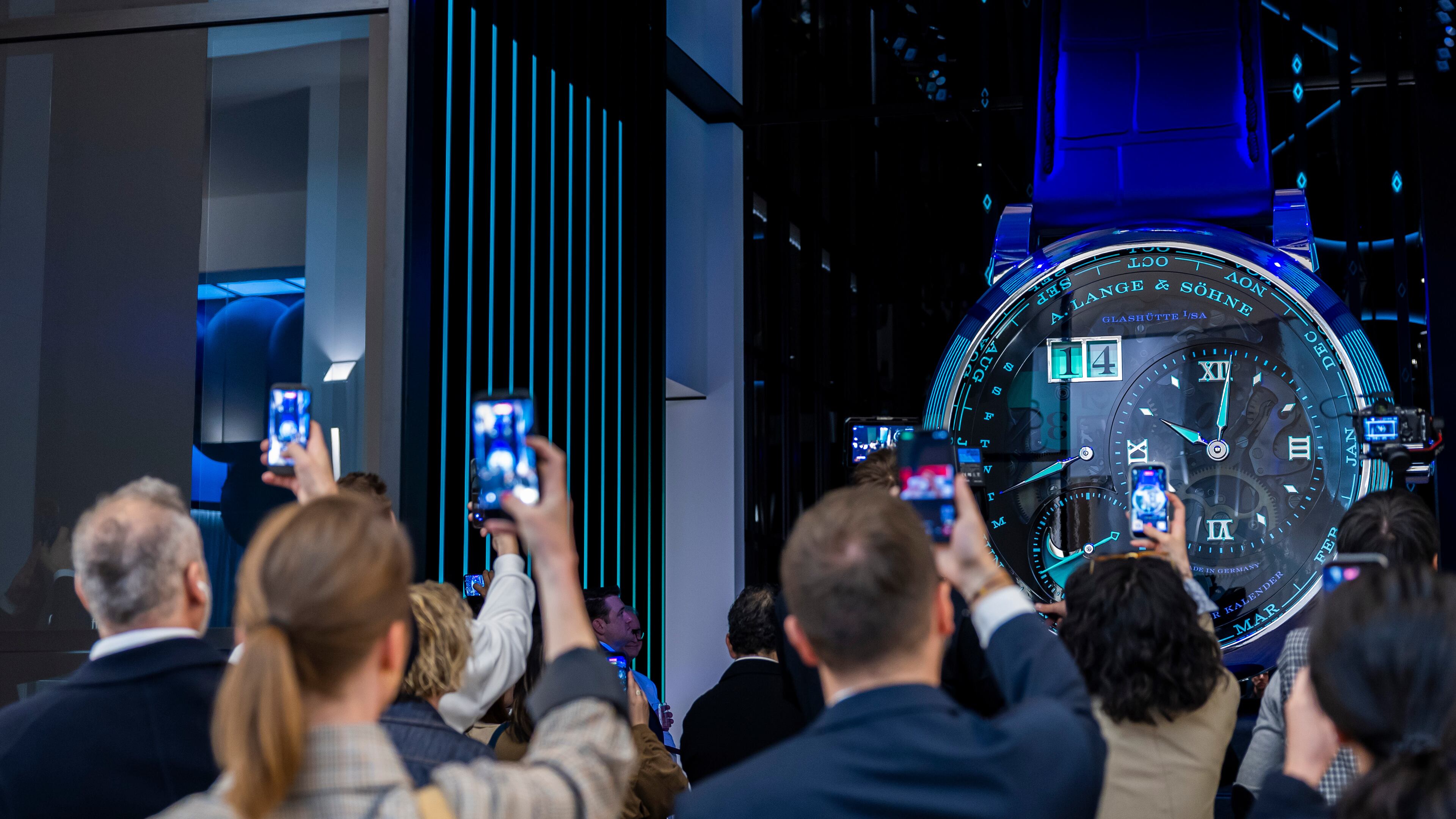 Visitors take photos with their smartphones of a watch at the German watch manufacturer A. Lange & Shone stand, during the opening day of the "Watches and Wonders Geneva" luxury watch fair, in Geneva, Switzerland, Tuesday, April 14, 2026. (Salvatore Di Nolfi/Keystone via AP)