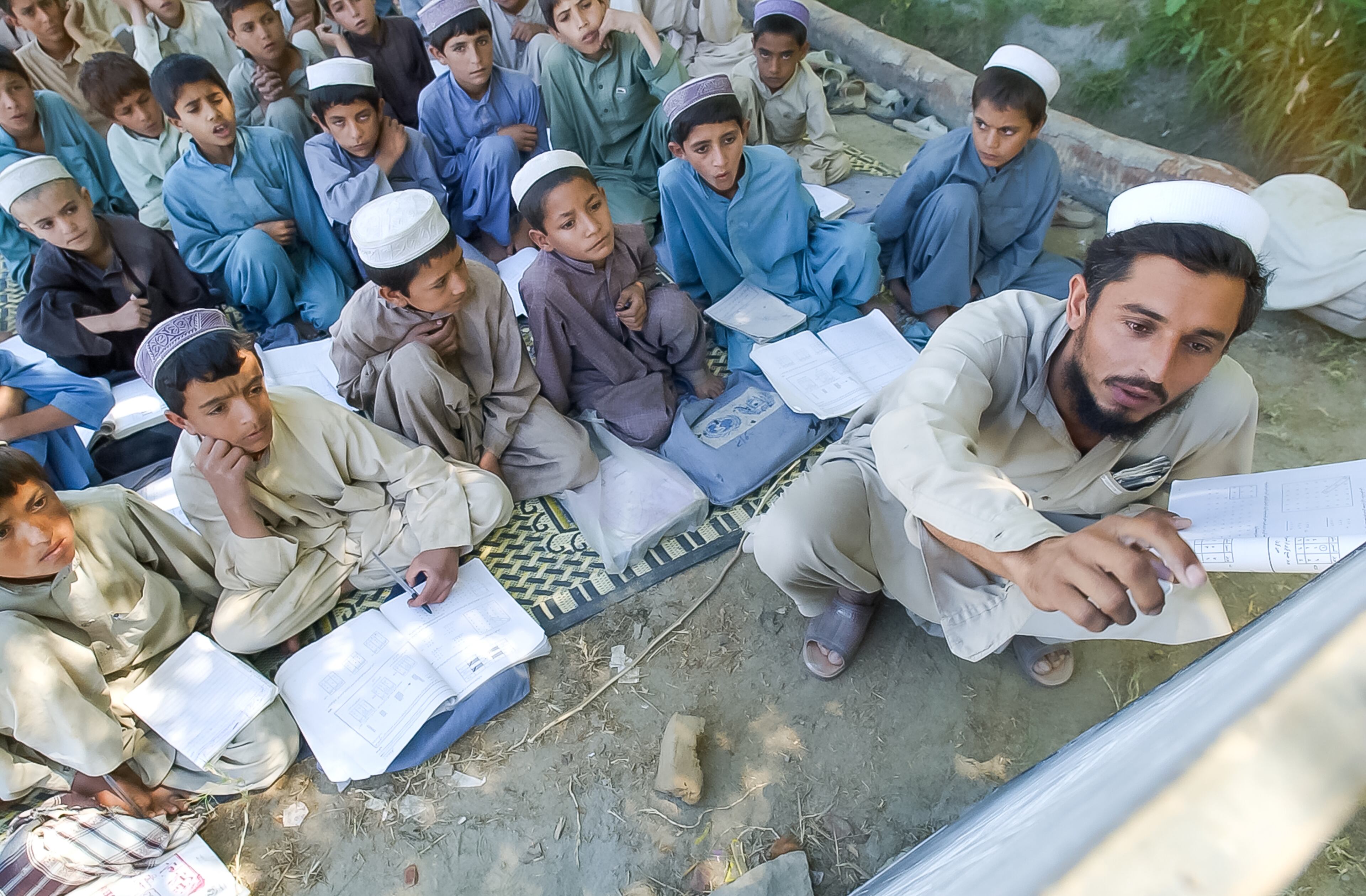 PACHIR, AFGHANISTAN: Students at the Kozgam School, a UNICEF-sponsored school in Pachir, Afghanistan, pay attention as their teacher reviews a math problem Thursday, Sept. 5, 2002. Pachir is a small village in the east of Afghanistan, just south of Jalalabad on the road to Tora Bora. There were three tents housing male students, but none for female students because, a teacher said, there was no room in the village for facilities for girls. (Bita Honarvar / The Atlanta Journal-Constitution)