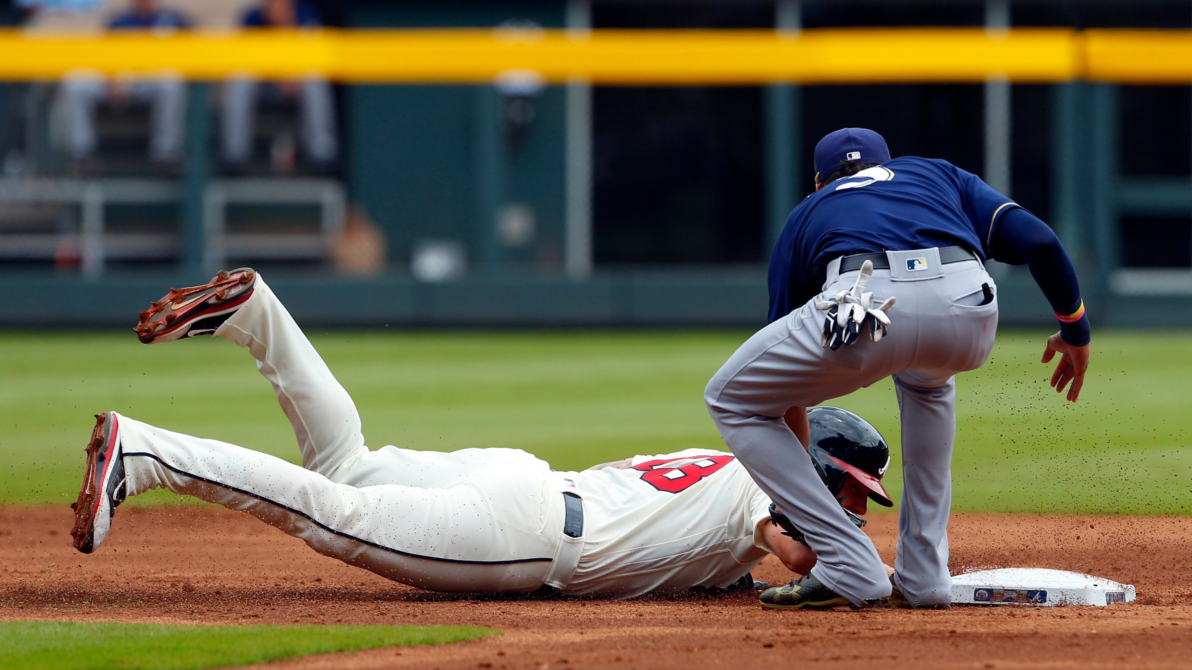 Matt Adams is tagged out by Brewers shortstop Orlando Arcia as he dives back to second base during Sunday's game at SunTrust Park.