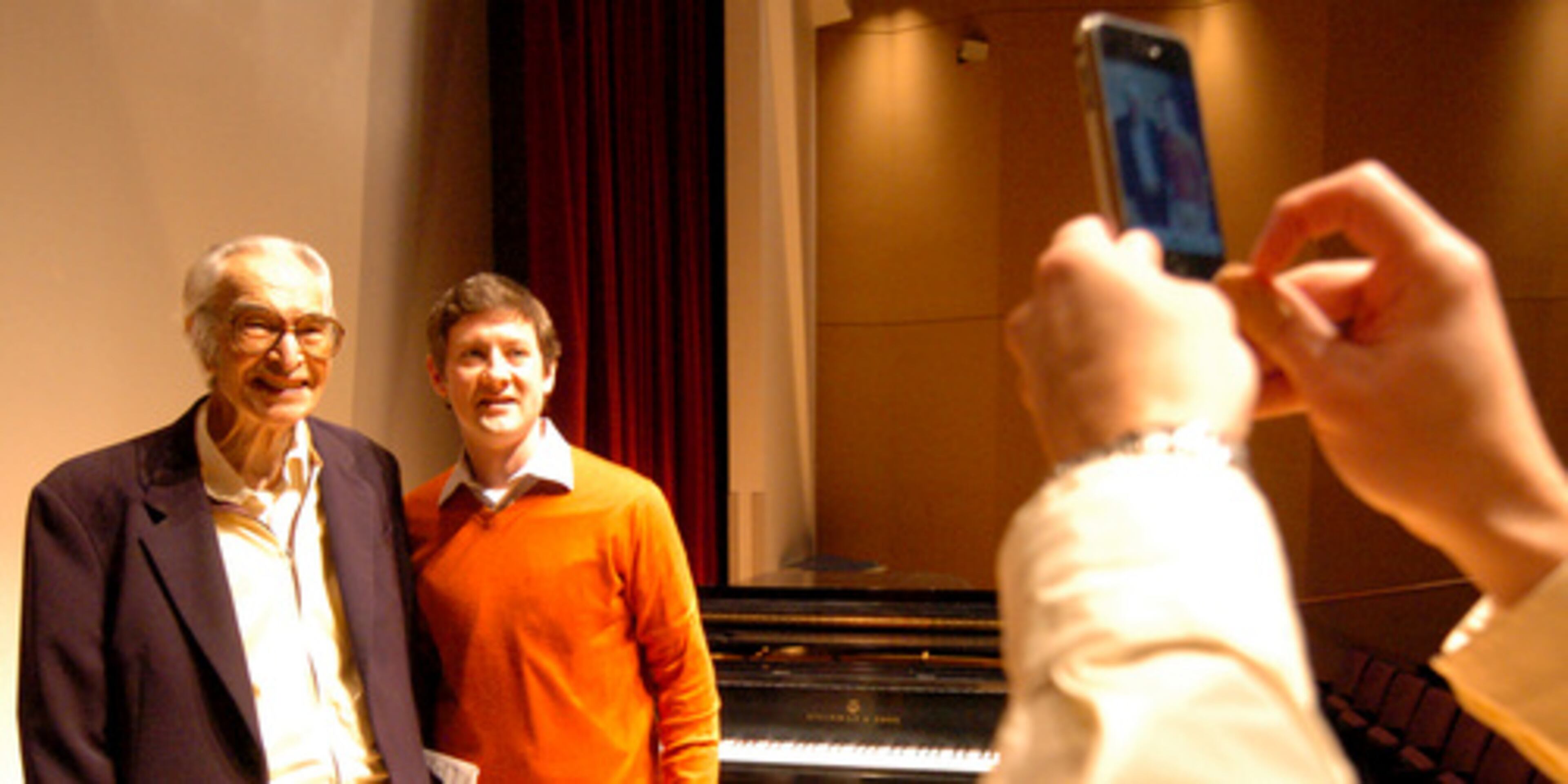 Brubeck poses with Chester Phillips, a doctoral student of conducting, as Phillips' friend takes a photo with an iPhone.