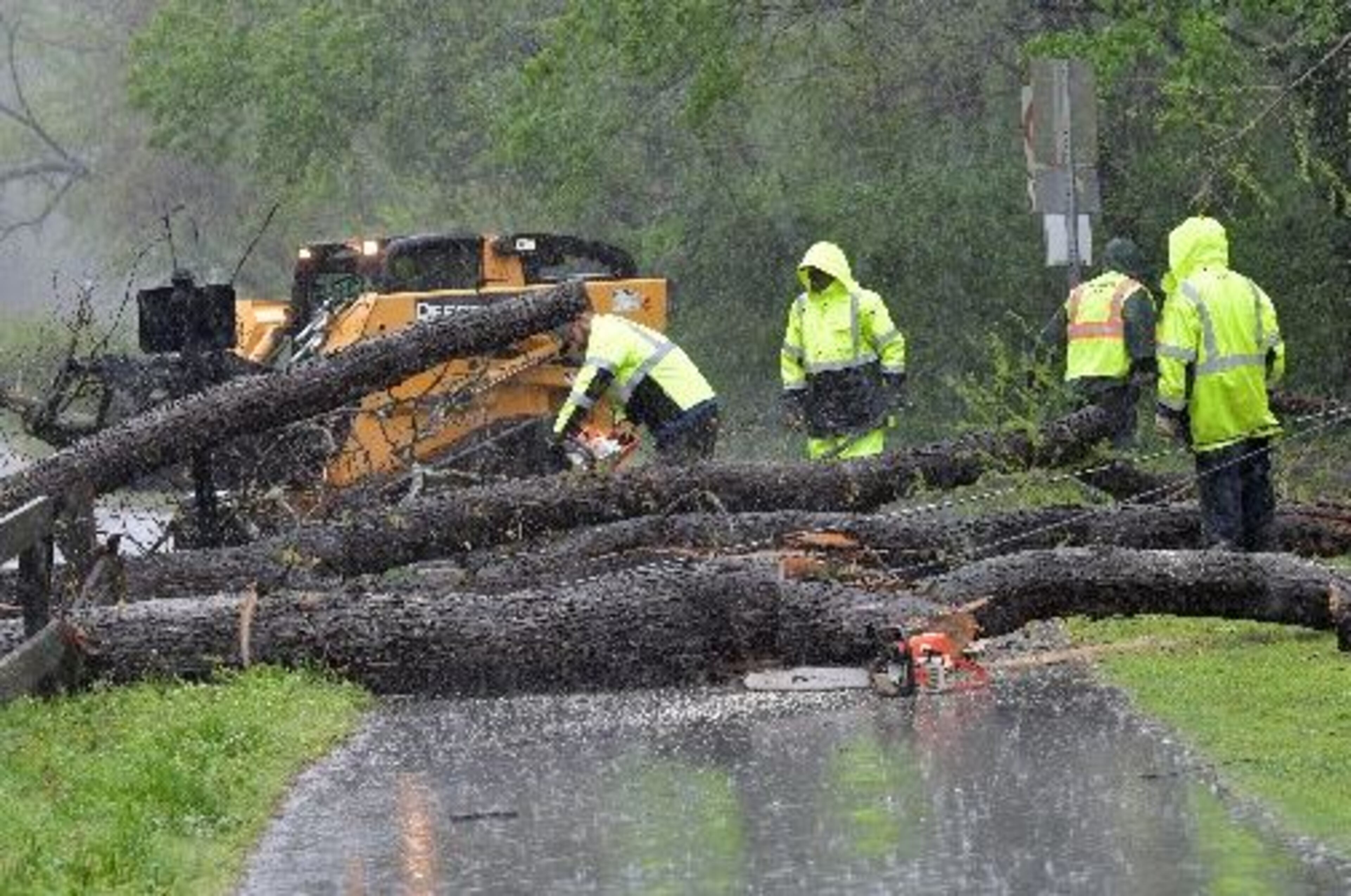 Workers clean up fallen trees on Azalea Drive near Avia Riverside Apartments in Roswell on Wednesday. HYOSUB SHIN / HSHIN@AJC.COM