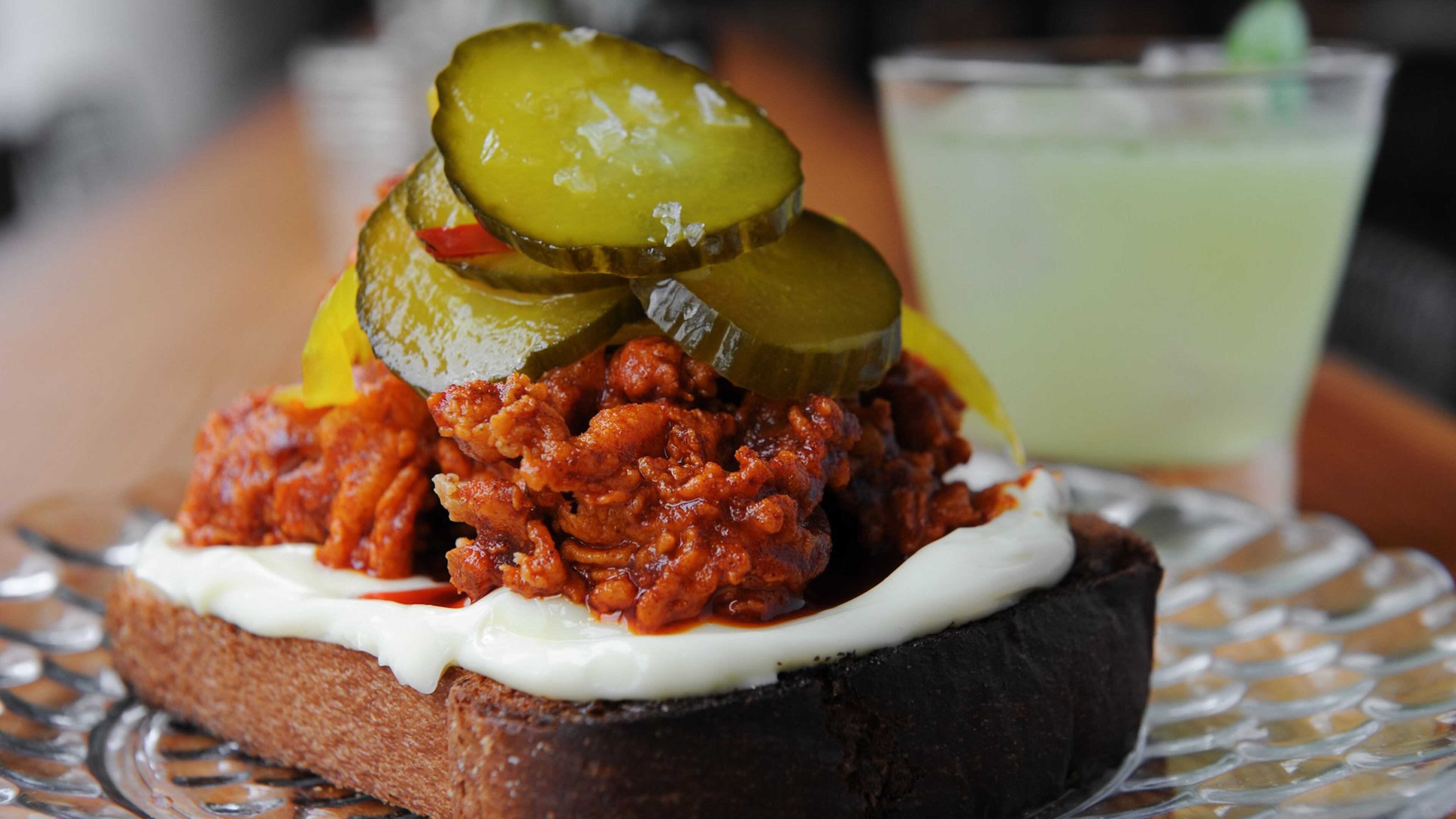 Grain’s hot oysters dish consists of fiery red fried oysters atop a thick piece of toasted brioche with a generous smearing of Duke’s mayonnaise, plus pickles. The drink is a Boxcar Racer — Bacardi 8 rum, peppercorn, lime and mint. (Becky Stein / www.beckysteinphotography.com)