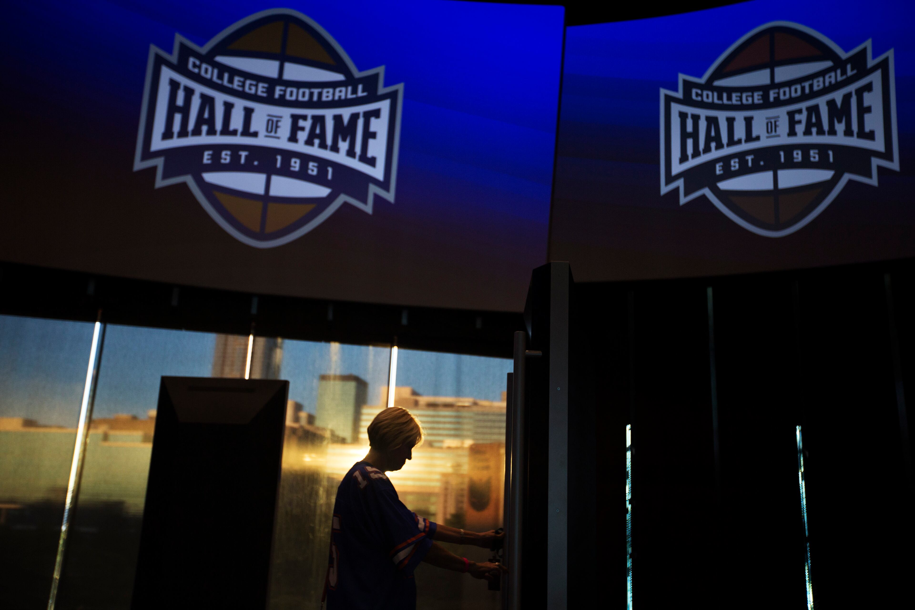 Valerie Herriman, of Augusta, Ga., tours the College Football Hall of Fame before spending the night there as the sun sets against the downtown skyline in the background, Wednesday, Aug. 13, 2014, in Atlanta. One hundred contest winners who wrote an essay detailing their love of college football were selected to stay with a guest overnight in Atlanta�s College Football Hall of Fame before its grand opening and win a year�s supply of Chick-fil-A. (AP Photo/David Goldman)