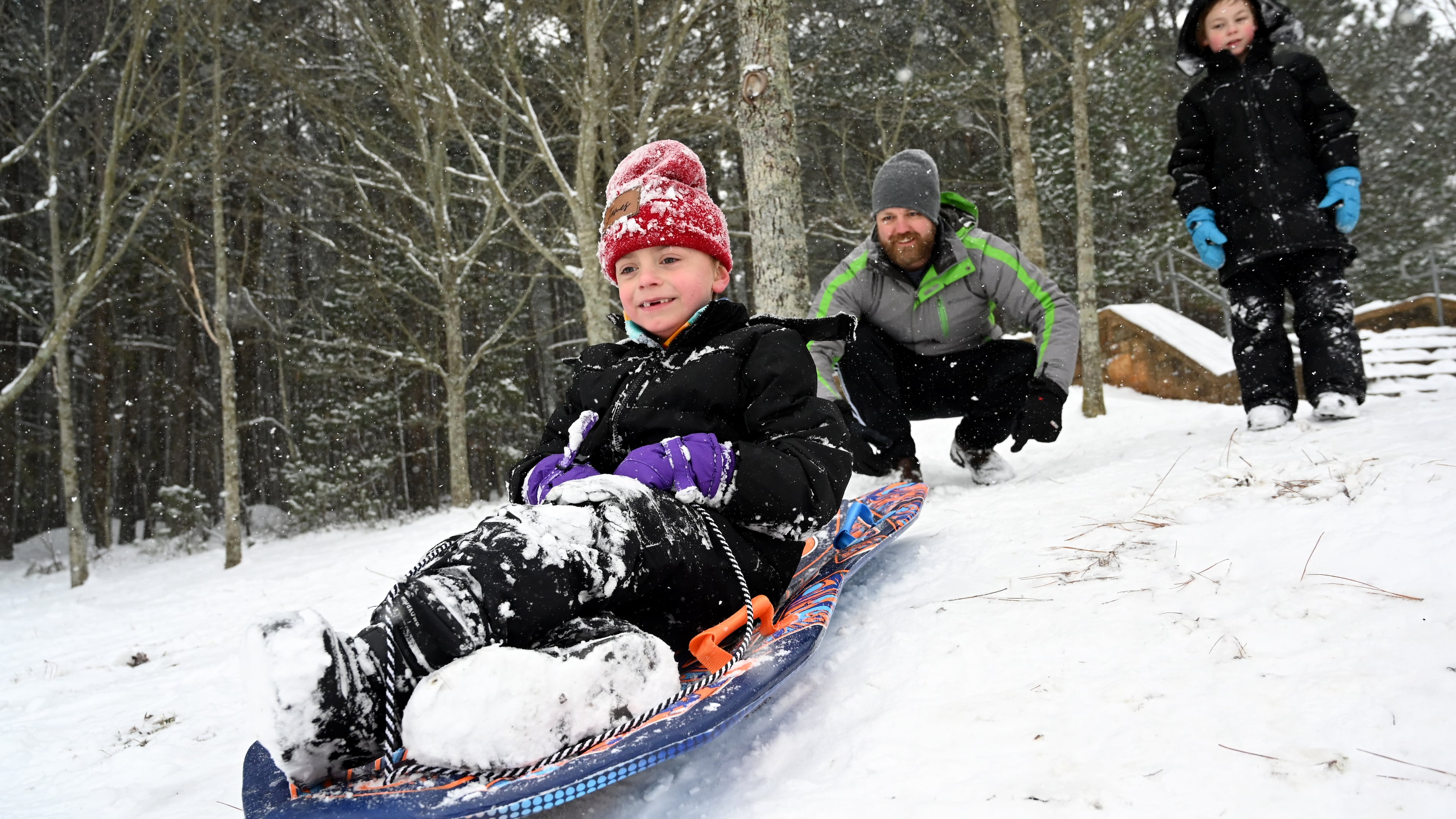 James Myers, 7, sleds down a hill as his father, Lee, pushes him at Little Mulberry Park on Saturday, Jan. 31, 2026, in Dacula. Snow turned parts of Middle and North Georgia, including metro Atlanta, into a snow globe. (Hyosub Shin/AJC)