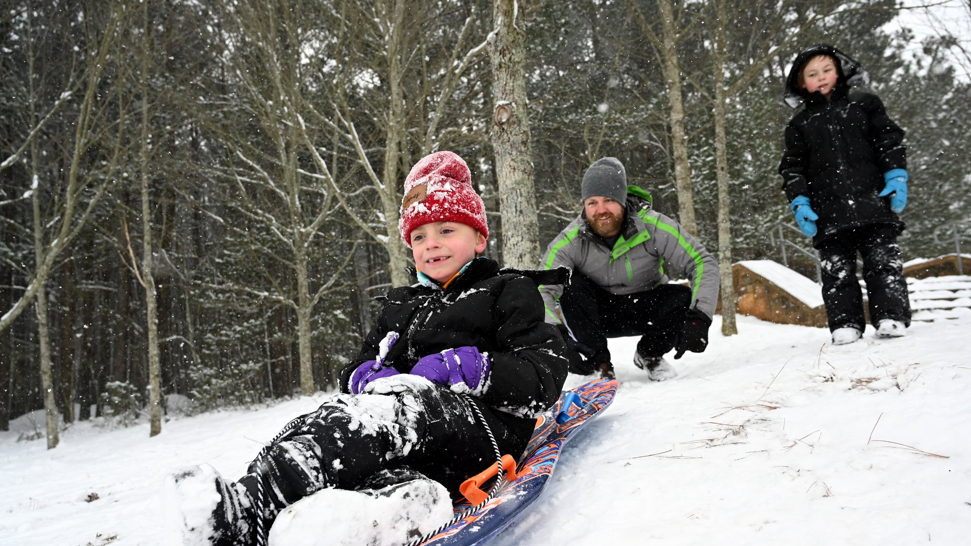 James Myers, 7, sleds down a hill Saturday as his father Lee Myers pushes him at Little Mulberry Park in Dacula, Georgia, north of Atlanta. (Hyosub Shin/AJC)