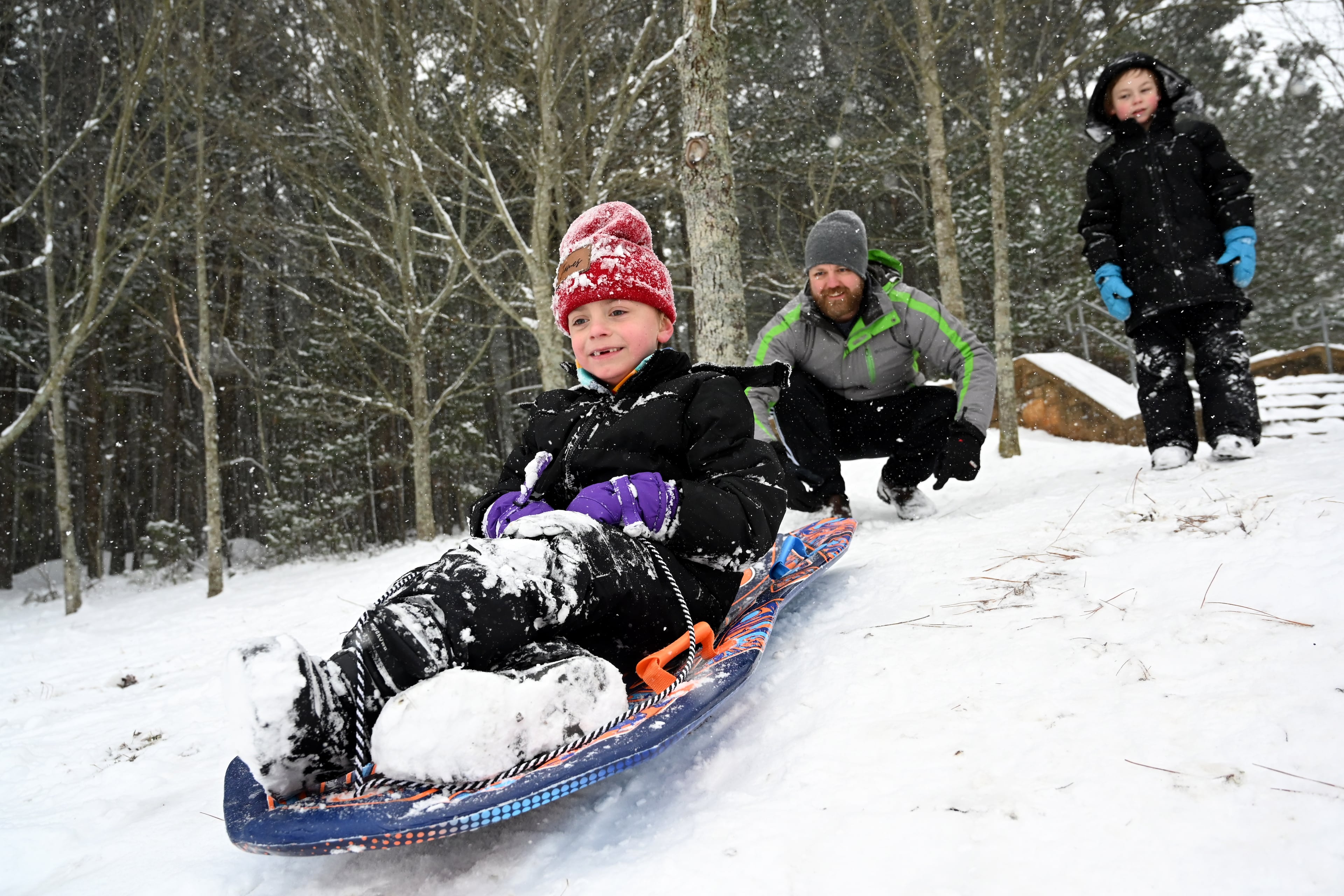 James Myers, 7, sleds down a hill as his father, Lee, pushes him at Little Mulberry Park on Saturday, Jan. 31, 2026, in Dacula. Snow turned parts of Middle and North Georgia, including metro Atlanta, into a snow globe. (Hyosub Shin/AJC)
