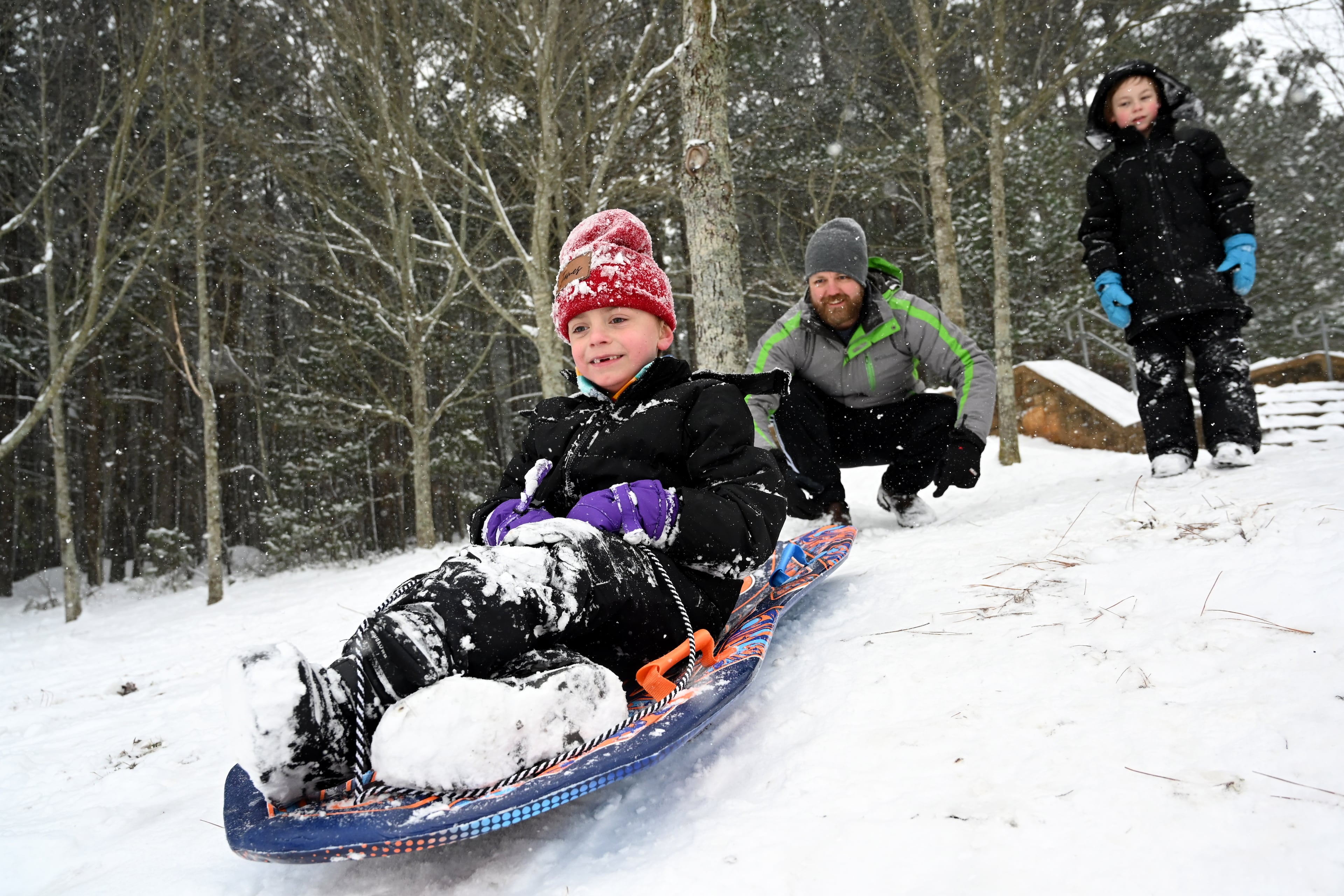 James Myers, 7, sleds down a hill Saturday as his father Lee Myers pushes him at Little Mulberry Park in Dacula, Georgia, north of Atlanta. (Hyosub Shin/AJC)