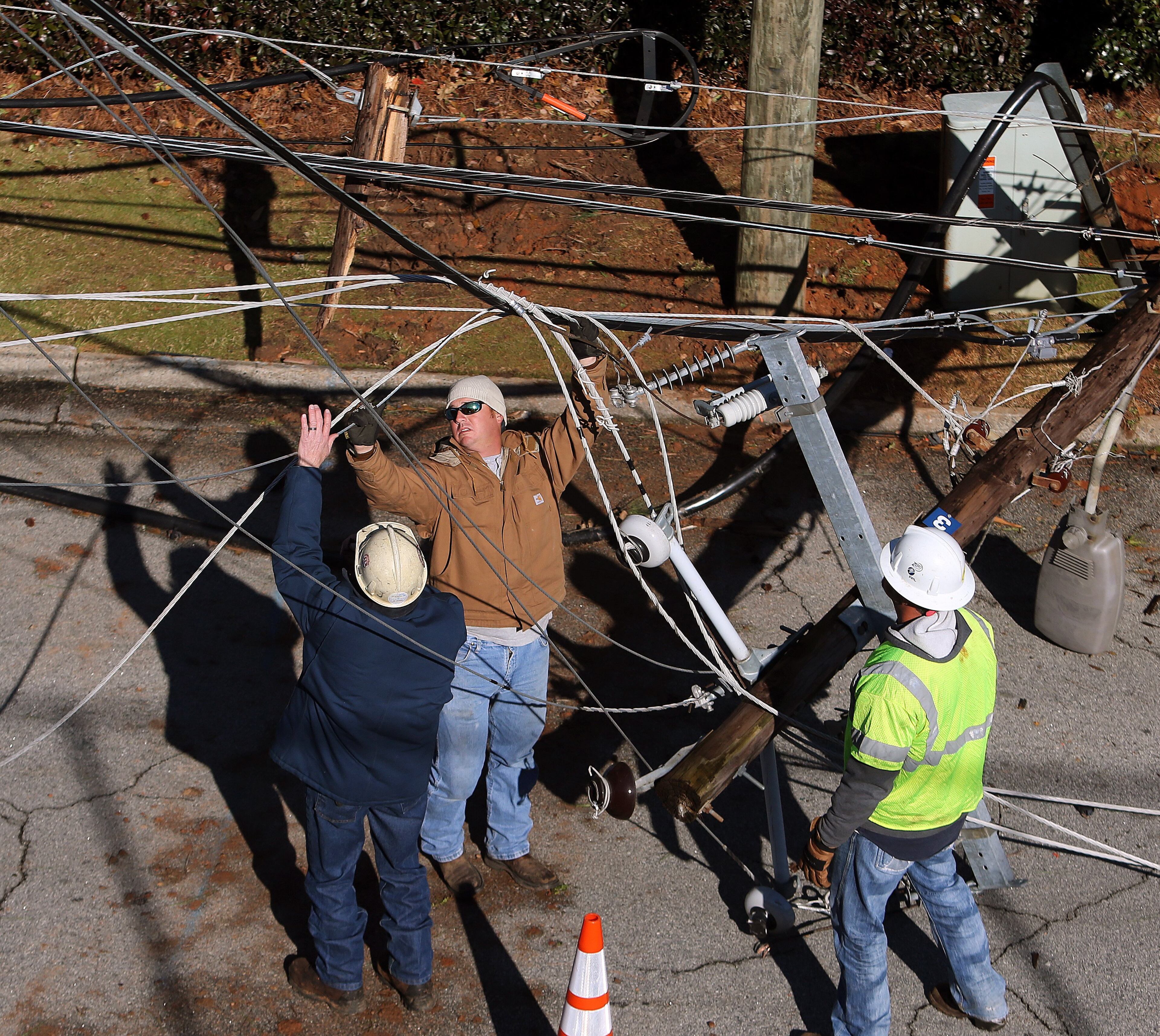 Florida Power and Light workers untangle a mess of power lines on a snapped pole in Augusta early Saturday morning February 15, 2014 while working to restore power to a neighborhood. BEN GRAY / BGRAY@AJC.COM