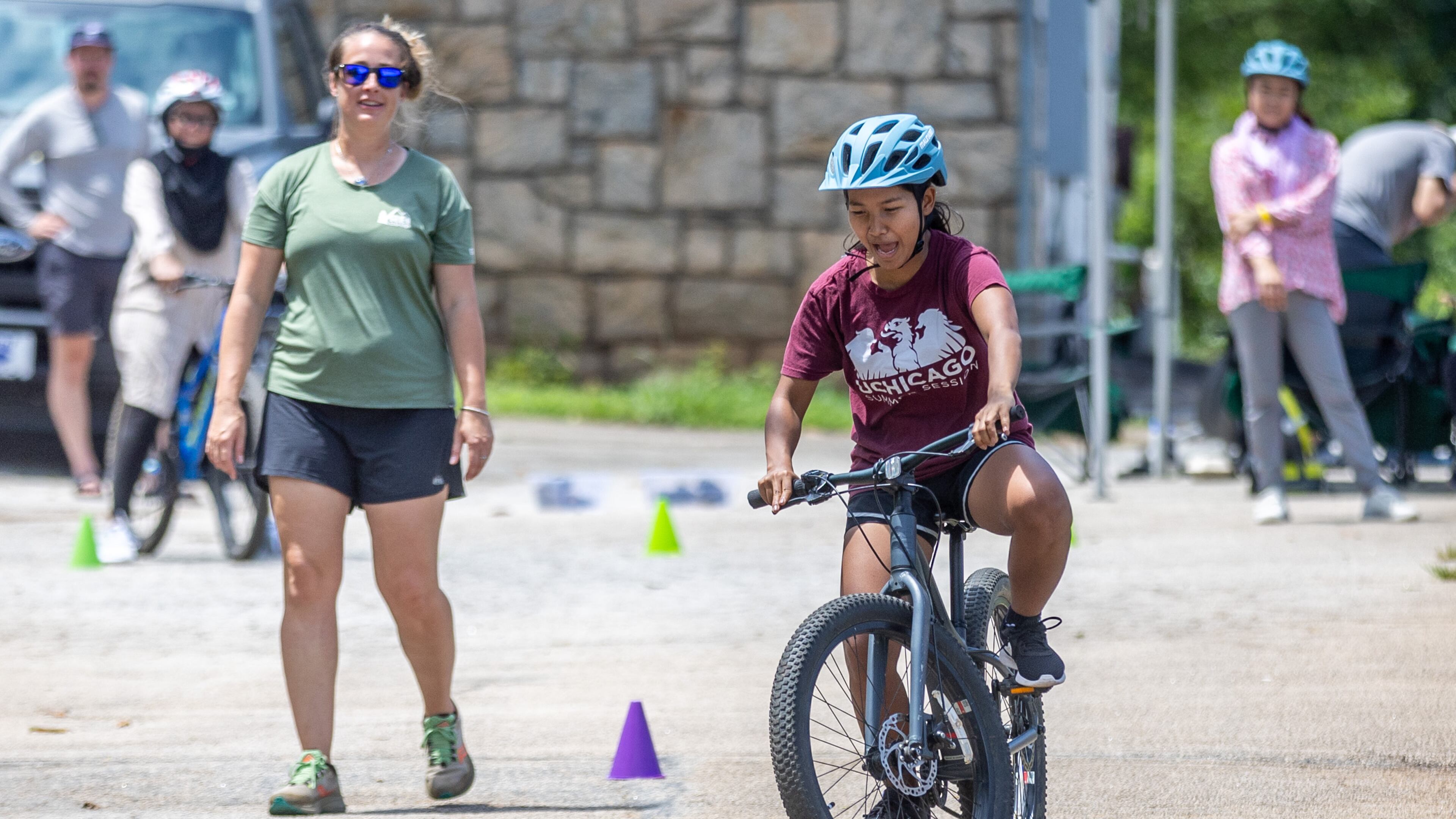 Instructor Ashley Clarkin watches Mang Bor Cin weave her bike through the cones during Mang Bor Cin's first bike riding lesson in Decatur Saturday. July 23, 2023. (Steve Schaefer/steve.schaefer@ajc.com)
