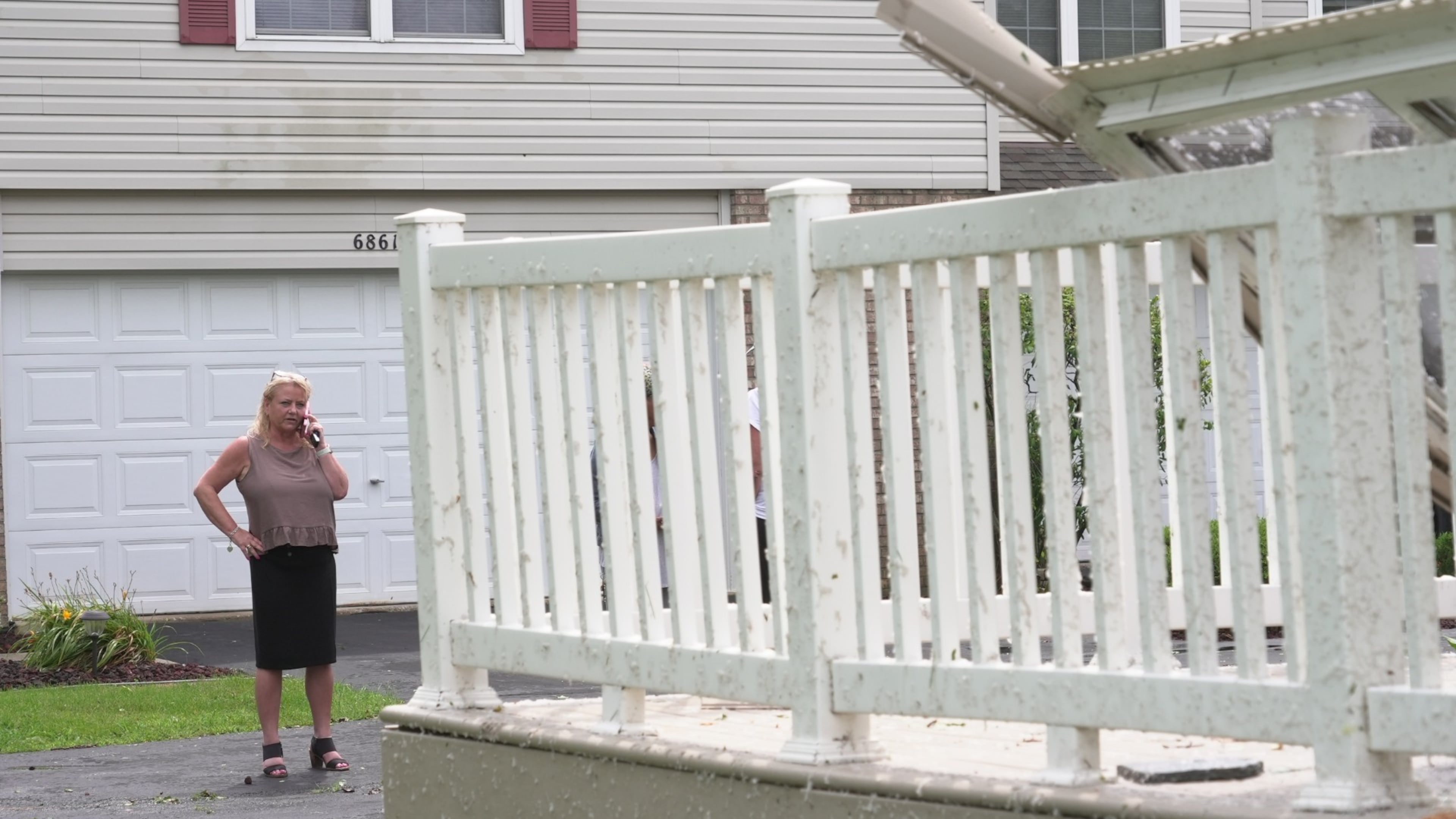 Kerry Hourigan speaks on the phone after reviewing damage a storm caused to her home in Tinley Park, Ill., Tuesday, Aug. 11, 2026. (AP Photo/Laura Bargfeld)
