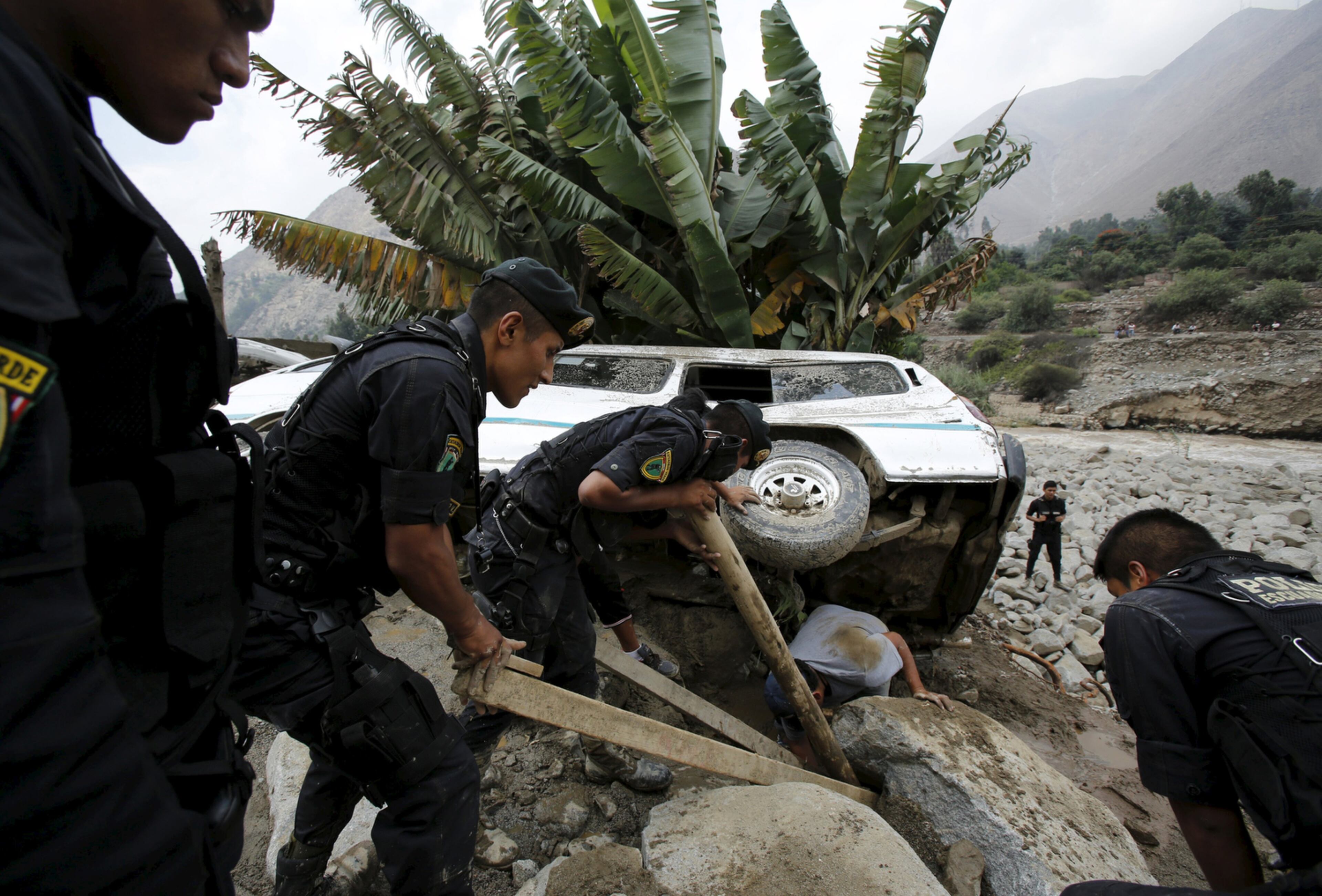 PERU LANDSLIDE--Peruvian police try to remove a car that was stuck in the mud and stones after a landslide in Chosica, March 24, 2015. Seven people were killed and more were feared dead in Peru after a massive landslide buried parts of a town amid heavy rains, authorities said on Tuesday. Six were missing and 25 injured in the disaster in Chosica, some 30 kilometers (18.6 miles) east of Lima, said Alfredo Murgueytio, the head of the National Civil Defense Institute, Indeci. REUTERS/Mariana Bazo