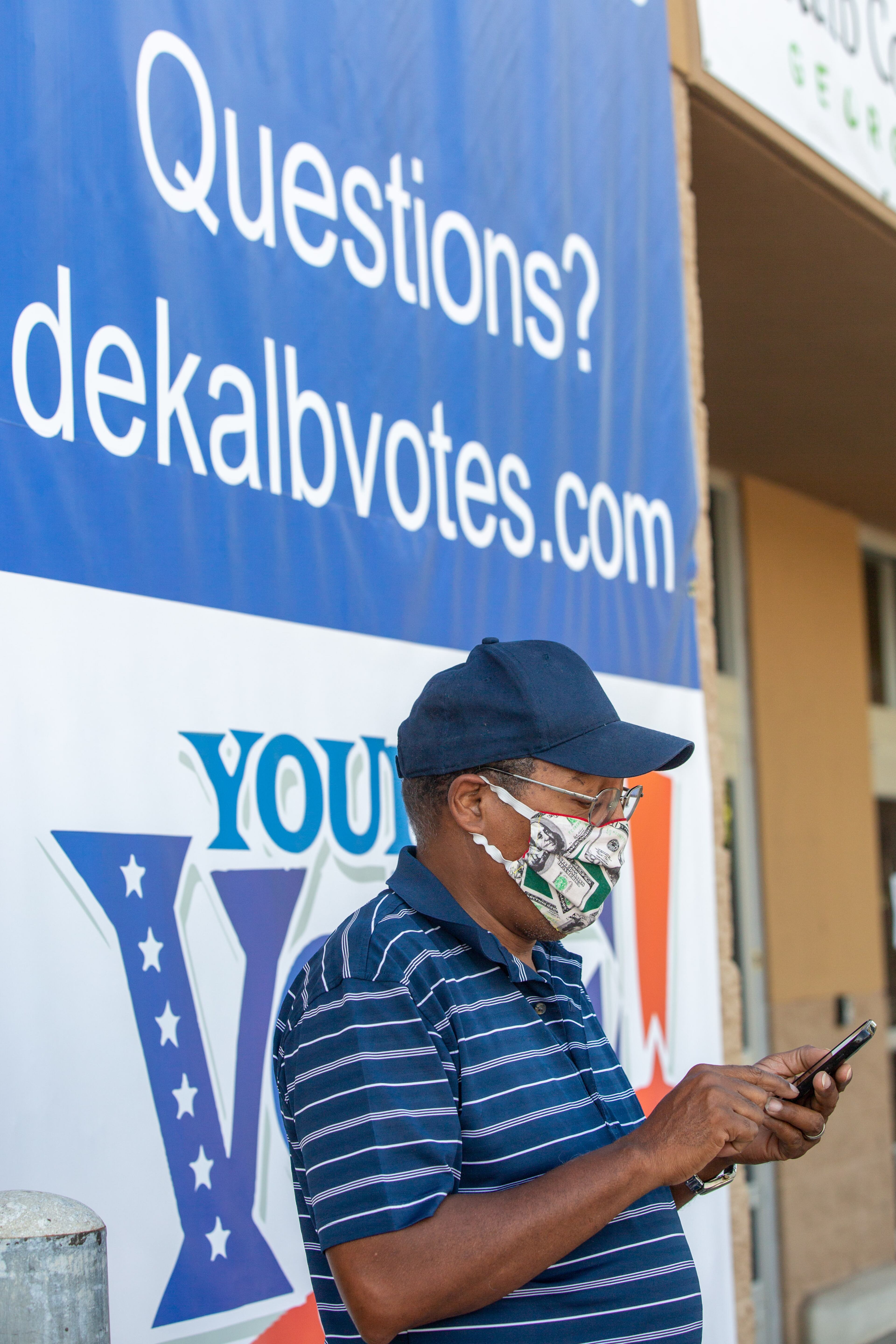 Carl Stephens checks his phone while waiting for his son to finish voting at the future Stonecrest City Hall in Stonecrest, Georgia, on Saturday, October 24, 2020. (Rebecca Wright for The Atlanta Journal-Constitution)