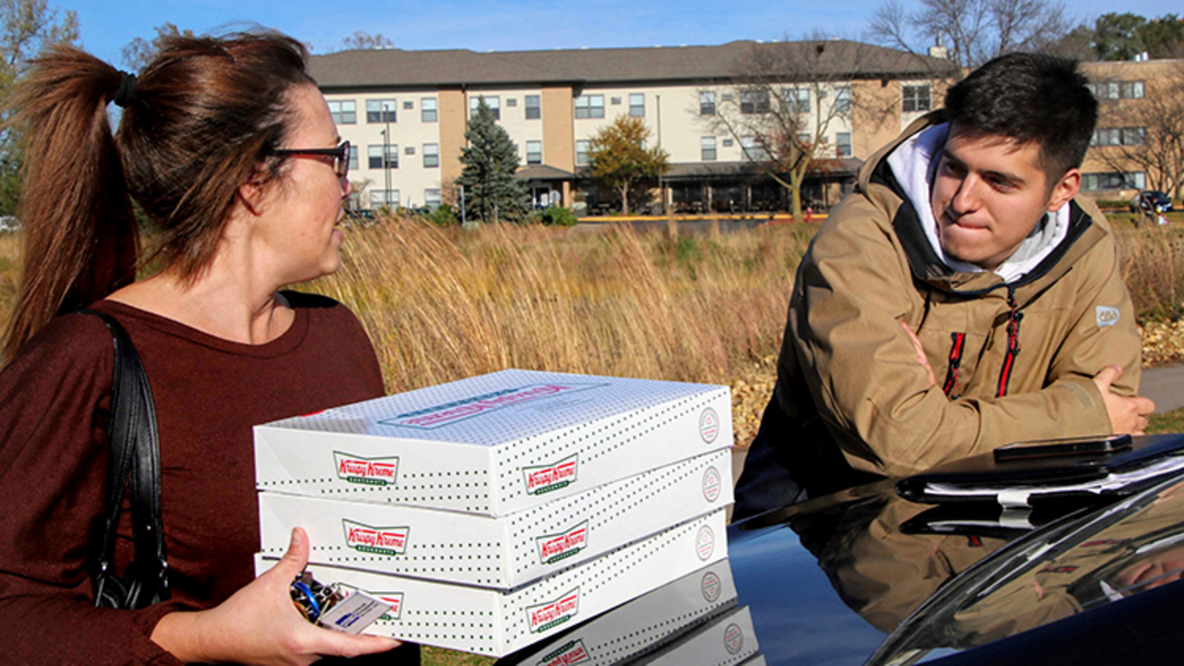 Catherine Newton buys three boxes of Krispy Kreme doughnuts from Jayson Gonzalez in Little Canada, Minn. Gonzalez, a Minnesota college student, says Krispy Kreme has told him to stop making doughnut runs to Iowa. Gonzalez told the Pioneer Press he was told his sales created a liability for the North Carolina-based company.