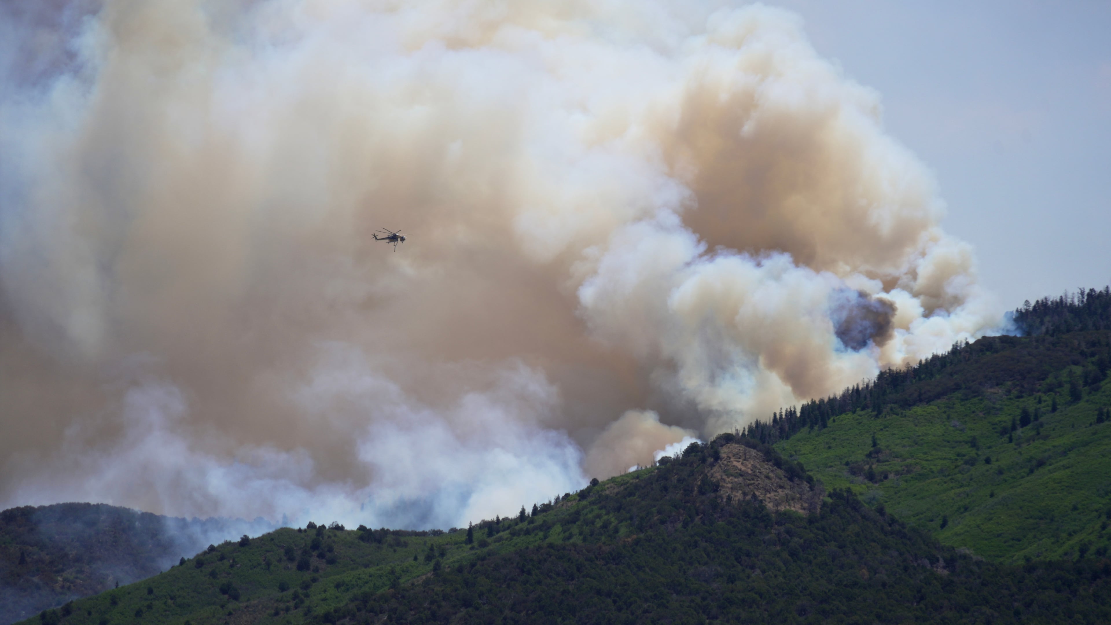 A helicopter flies near the Cottonwood Fire in Beaver, Utah, Tuesday, June 30, 2026. (AP Photo/Ty ONeil)