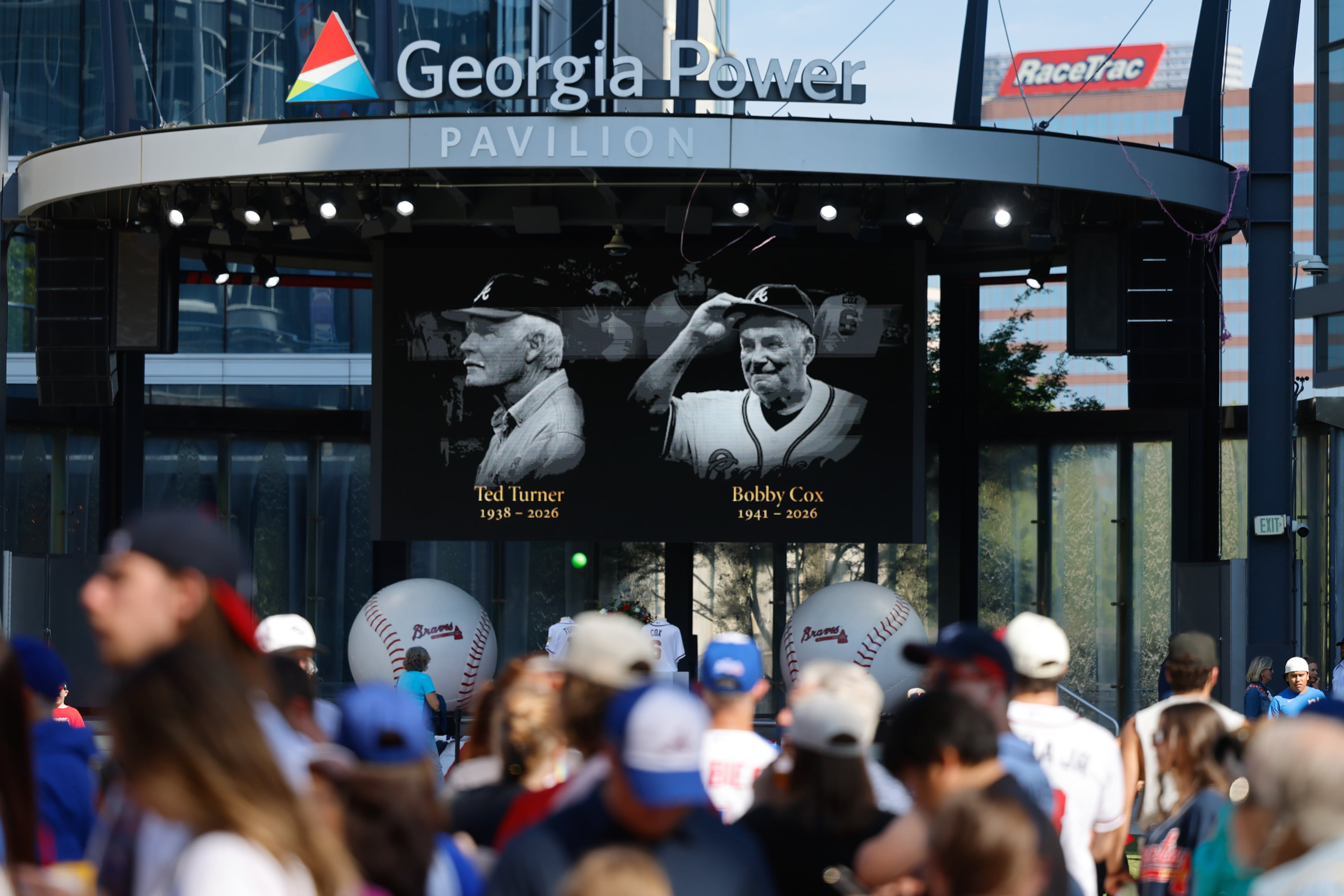Fans wait to get into the stadium near a tribute to the late CNN founder and former Braves owner Ted Turner, and late legendary Braves manager Bobby Cox at the Battery in Truist Park in Atlanta on May 12, 2026. (Arvin Temkar/AJC)
