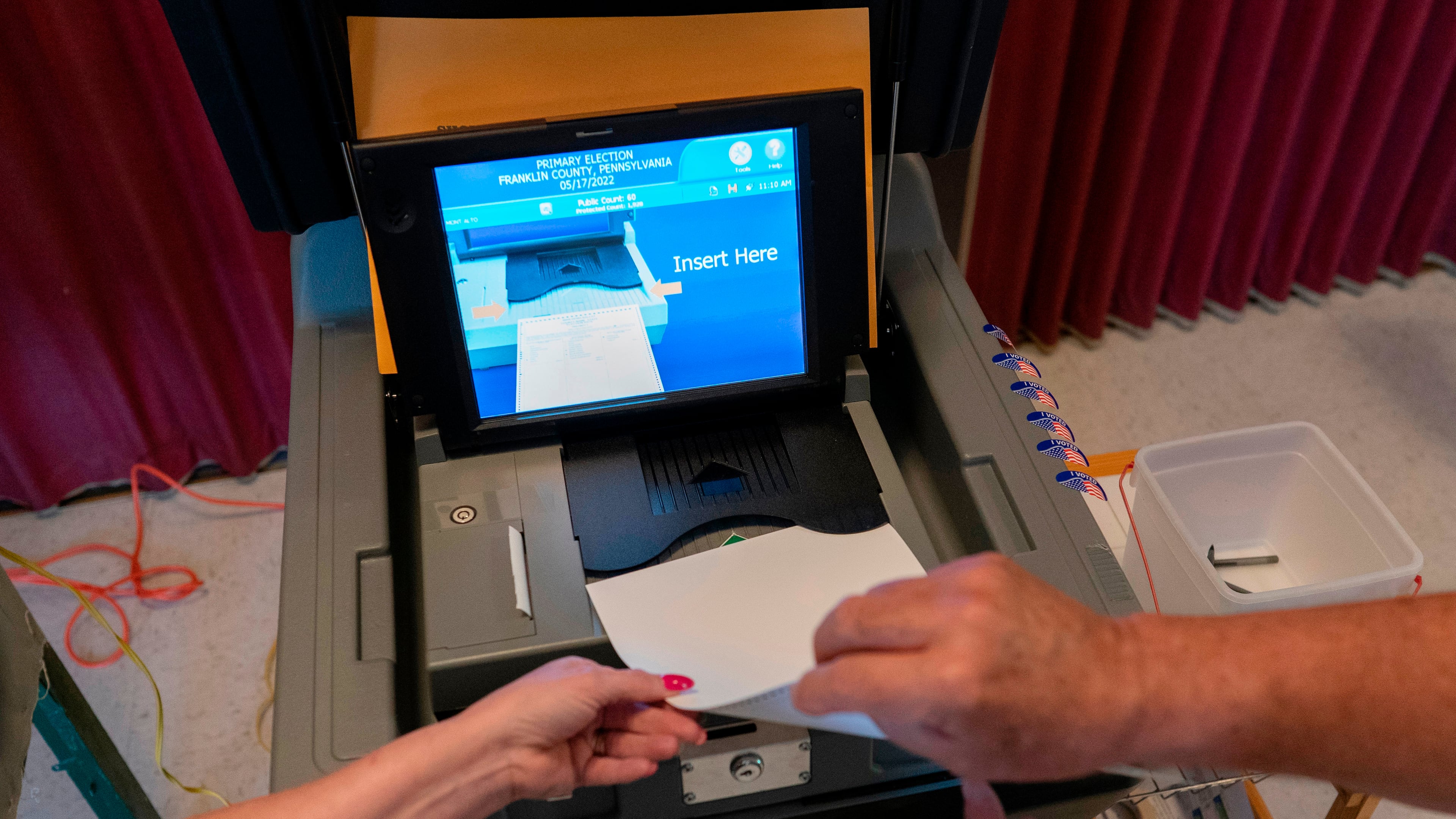 FILE - A polling judge, right, helps guide a voter's ballot into a voting machine during the Pennsylvania primary election, at Mont Alto United Methodist Church in Alto, Pa., on May 17, 2022. (AP Photo/Carolyn Kaster, File)