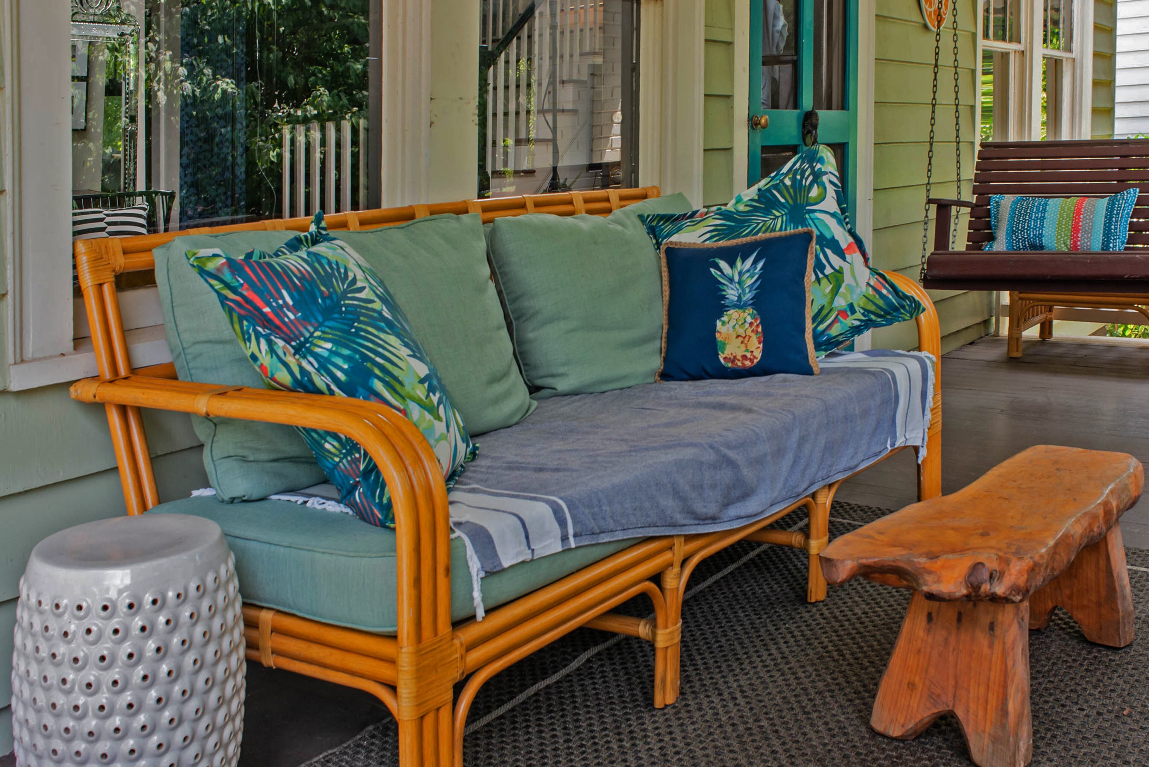 The front porch's rattan sofa is often a napping and reading spot. Colorful accents include the turquoise front door.