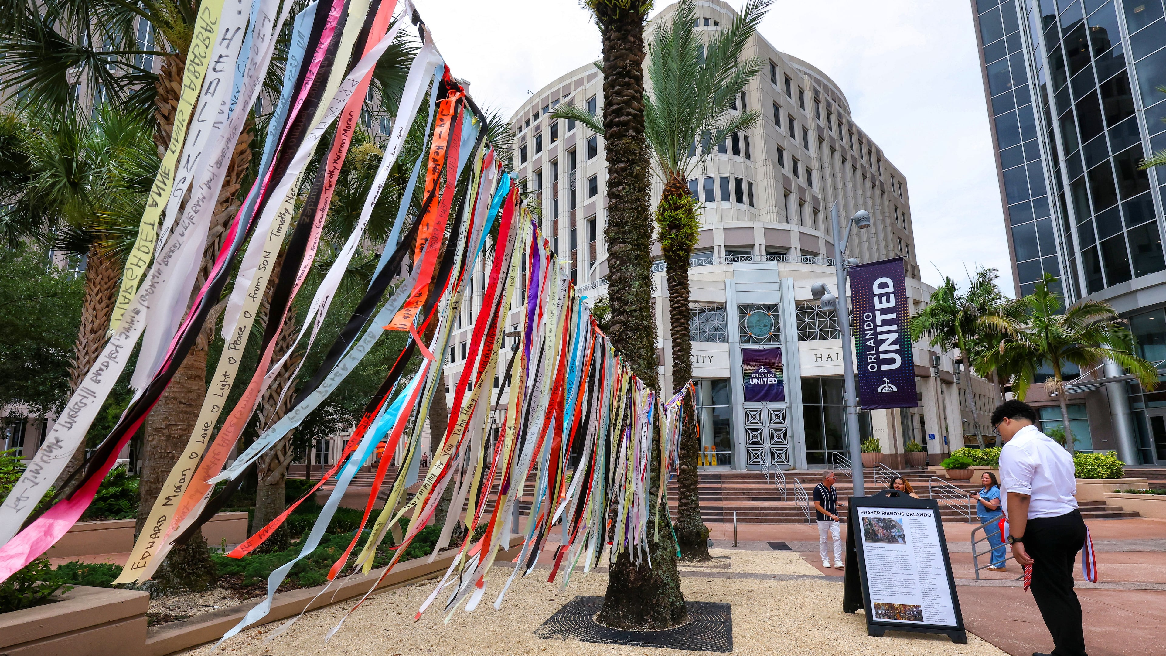 A person reads about the prayer ribbons honoring those killed in the 2016 Pulse nightclub shooting at Orlando City Hall, in Orlando, Fla., Tuesday, June 9, 2026. (Joe Burbank/Orlando Sentinel via AP)