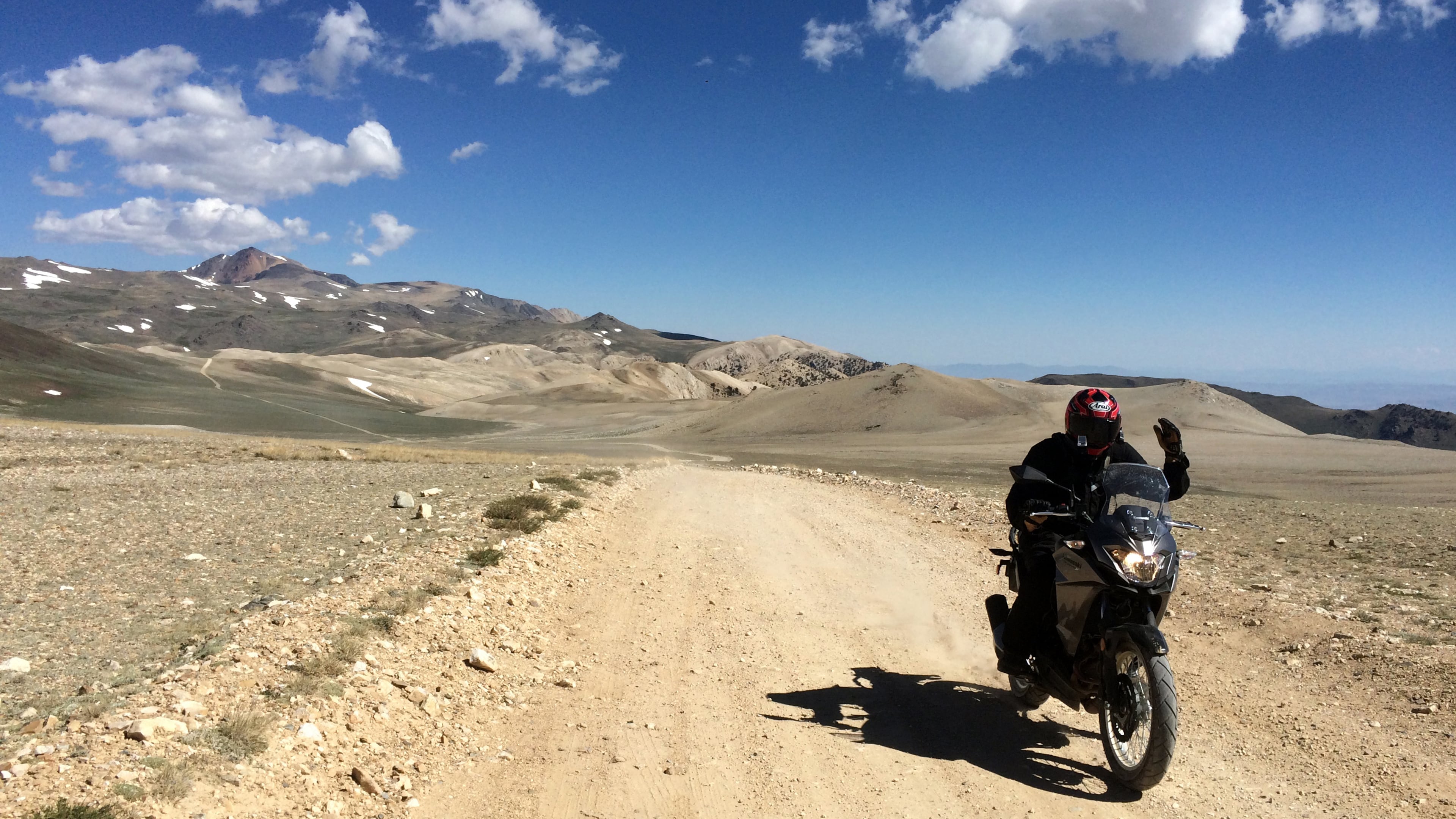 Riding companion Abhi Eswarappa waves as he rides by, with White Mountain far behind him. (Charles Fleming/Los Angeles Times/TNS)