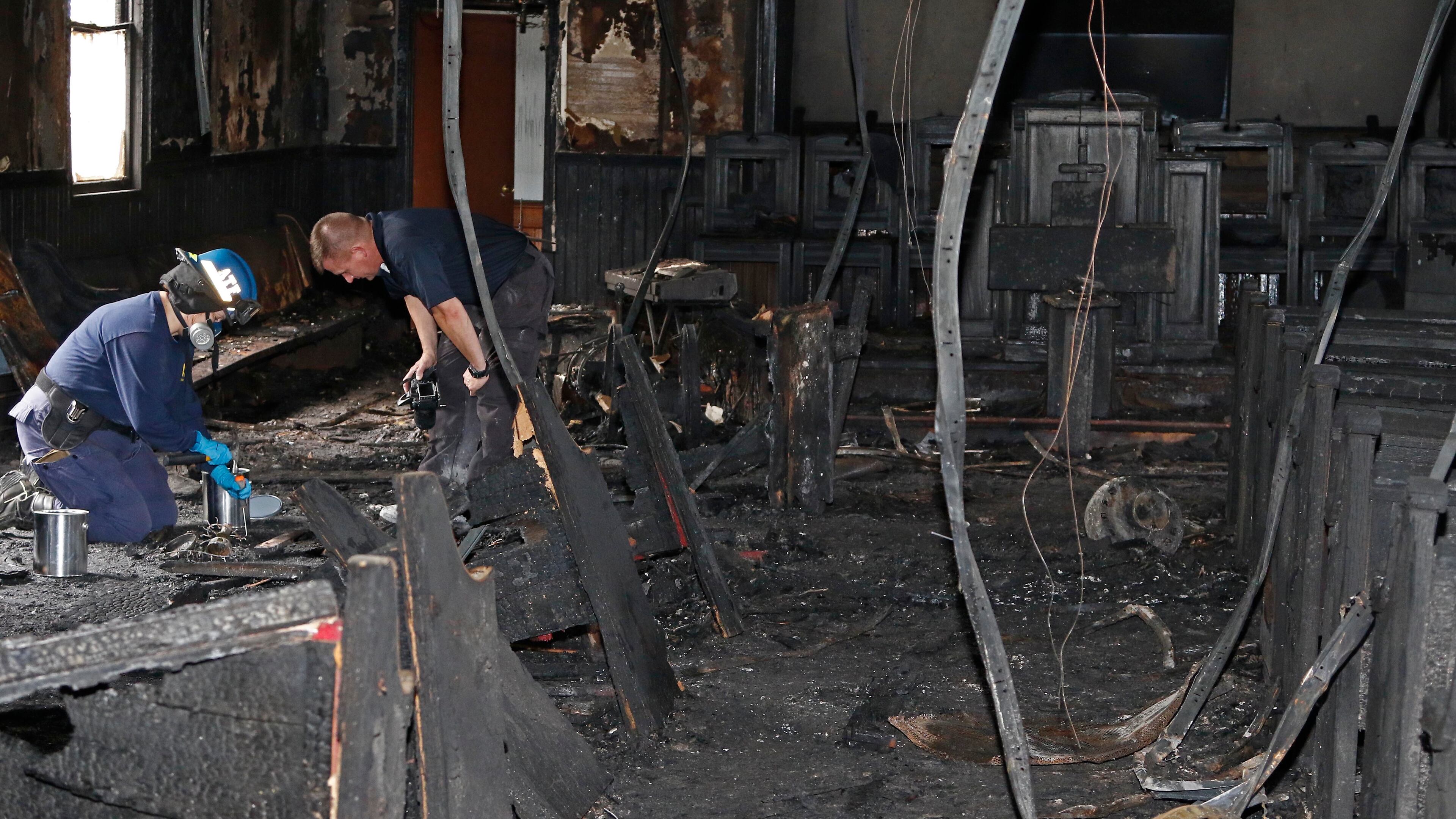 A state fire marshal, right, and a ATF agent collect evidence as they investigate the fire damaged Hopewell M.B. Baptist Church in Greenville, Miss., Wednesday, Nov. 2, 2016. "Vote Trump" was spray-painted on an outside wall of the black member church. Fire Chief Ruben Brown tells The Associated Press that firefighters found flames and smoke pouring from the sanctuary of the church just after 9 p.m. Tuesday. (AP Photo/Rogelio V. Solis)