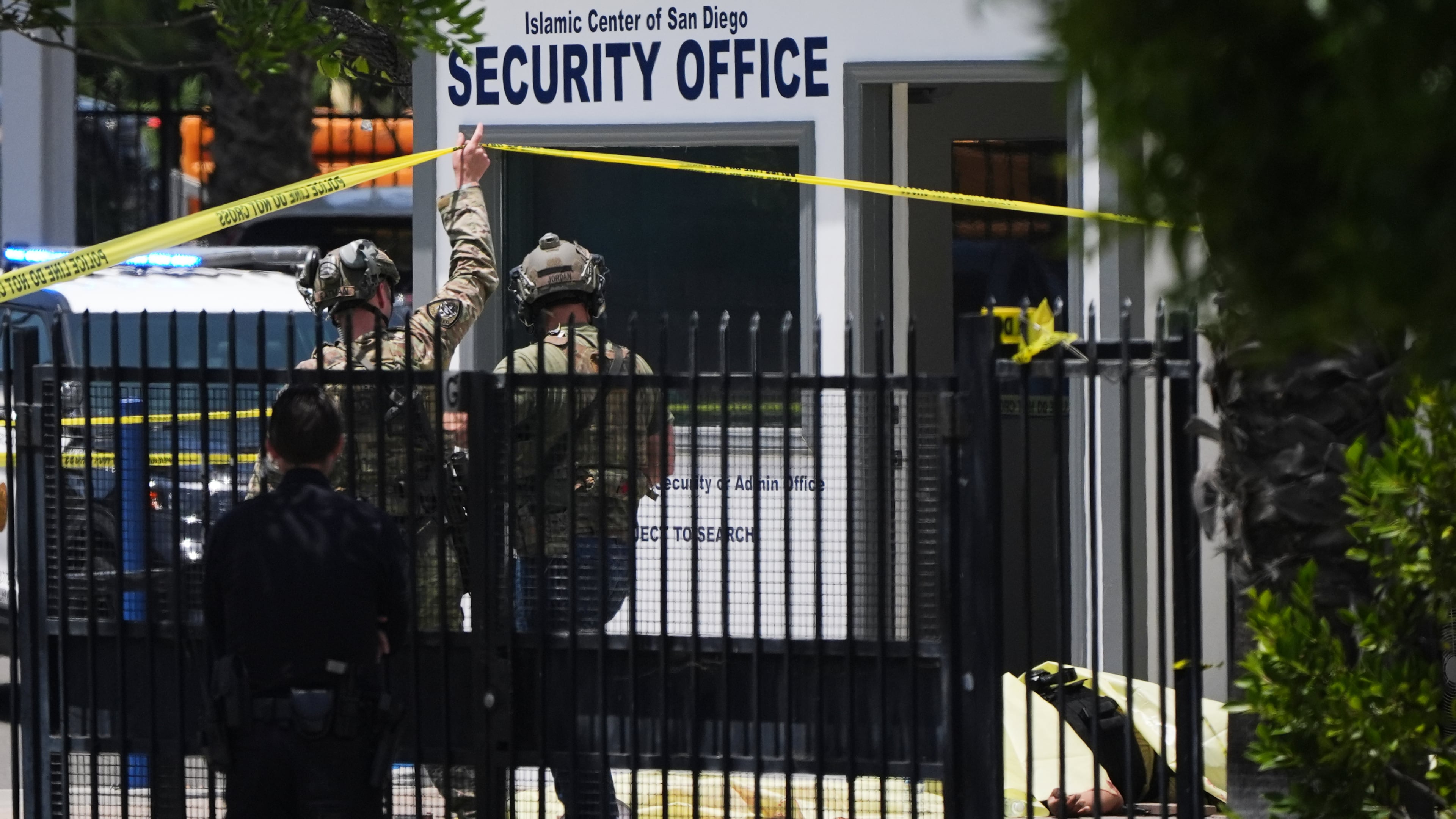 A body is covered with a tarp at the scene of a shooting outside the Islamic Center of San Diego Monday, May 18, 2026, in San Diego. (AP Photo/Gregory Bull)