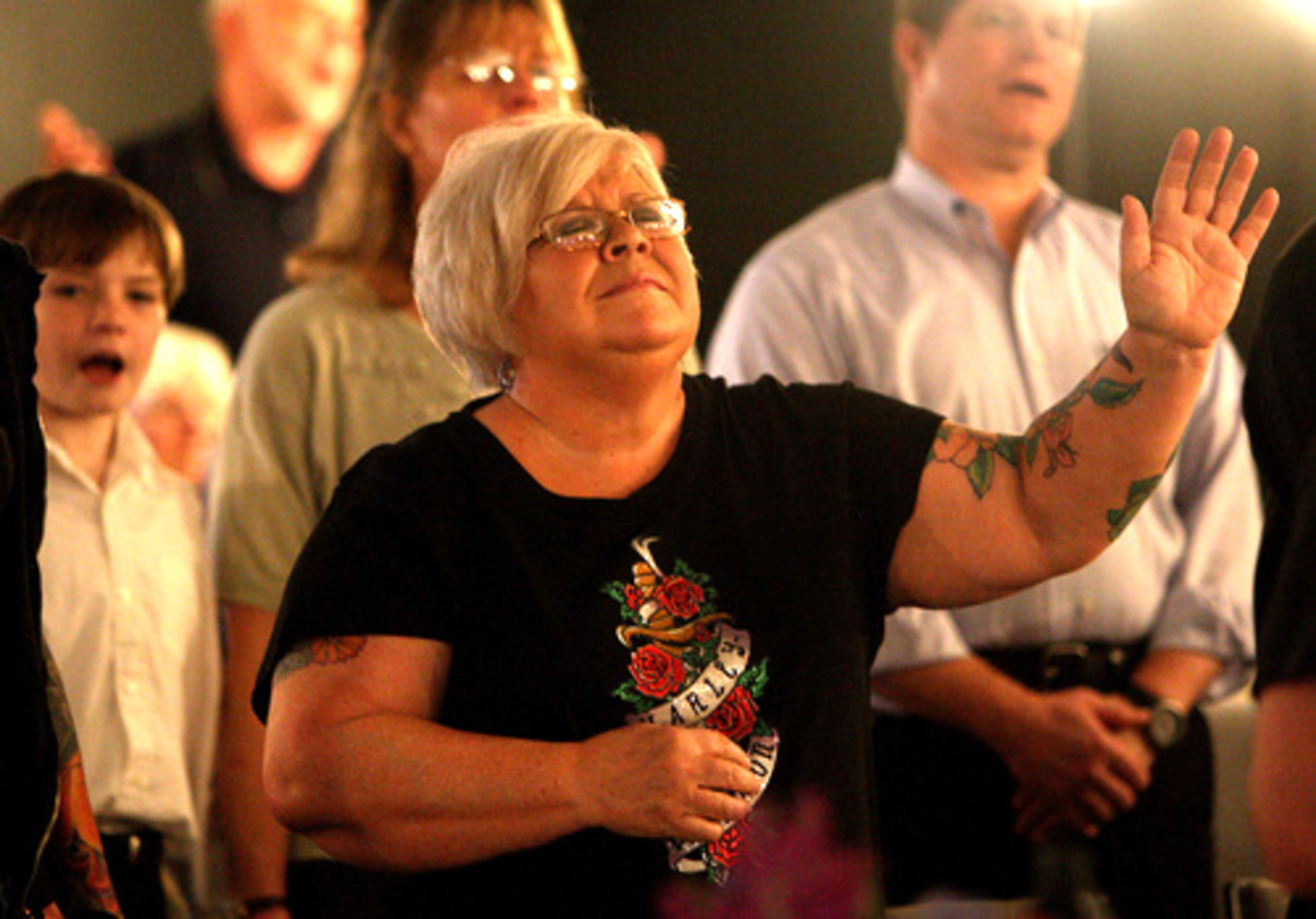Brenda Hamilton makes a praise sign as her husband, Tom Hamilton, 51, co-pastor of Sozo New Covenant Fellowship Church in Tucker plays the keyboard during a recent Sunday service.