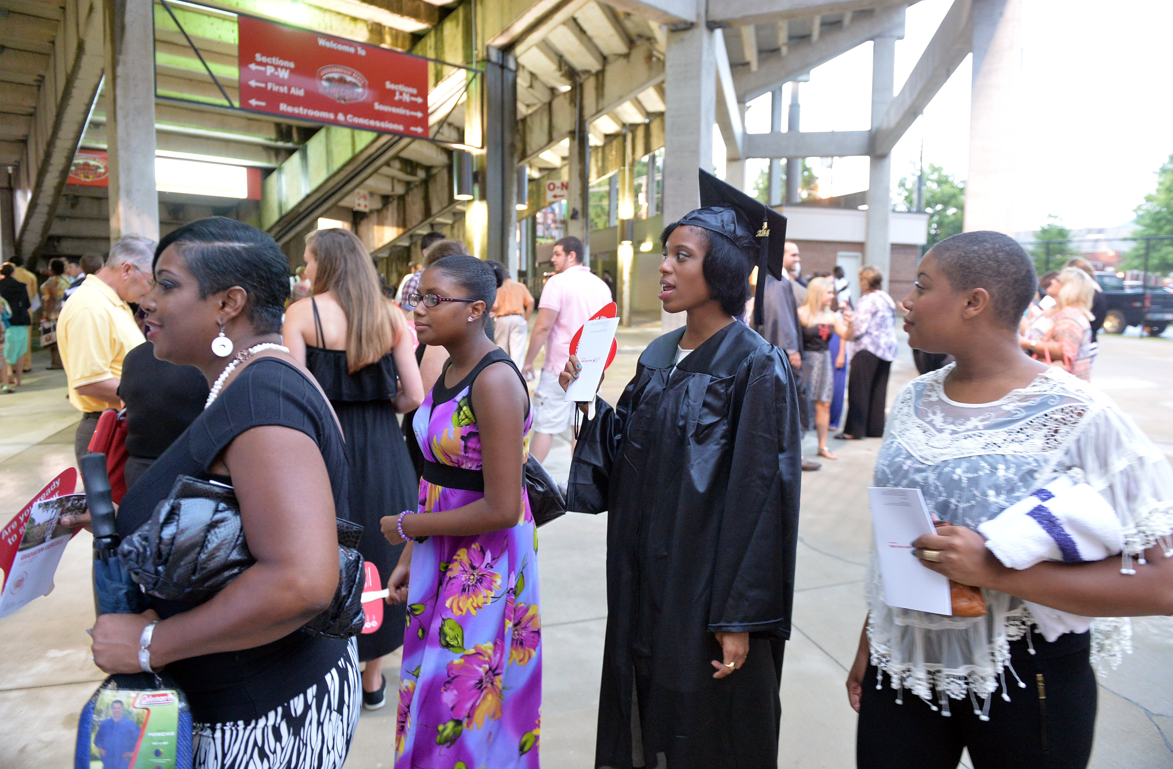 Aaron walks with her mother Joyce (left) and sisters Tayla and Maya into the stadium for graduation ceremonies. KENT D. JOHNSON / KDJOHNSON@AJC.COM