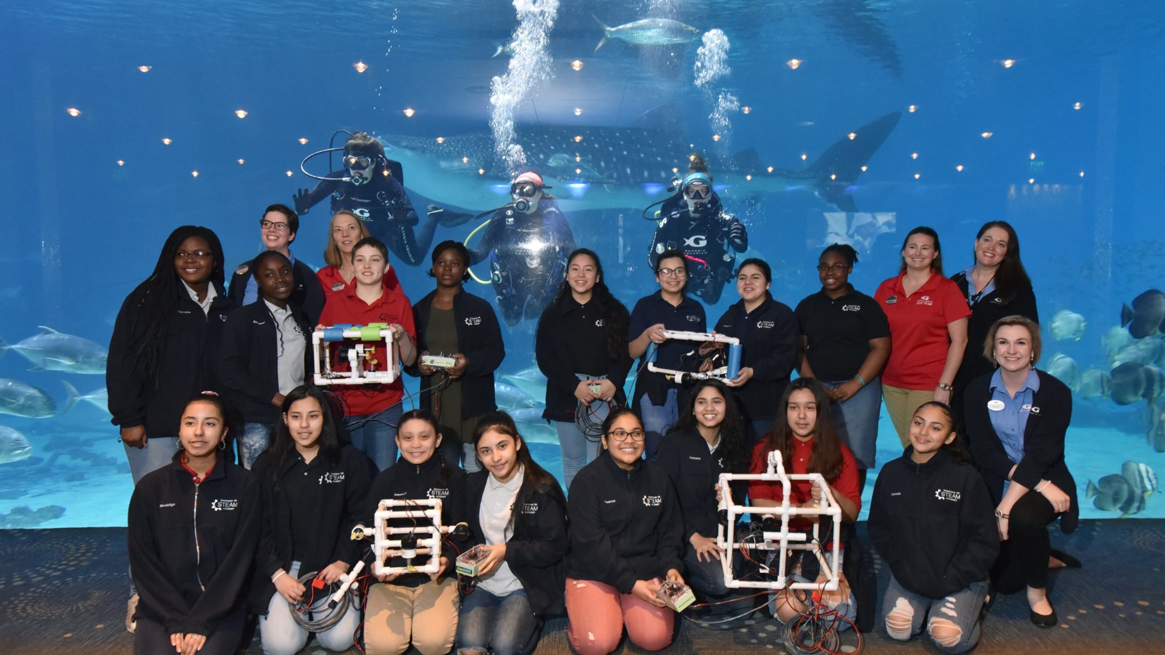 Students from Sweetwater Middle School and instructors pose with divers (from left) Susan Street, Lauren Schwitters and Kristen Binz for a group photograph during Girls Underwater ROV STEM Camp at Georgia Aquarium on Thursday, April 4, 2019. HYOSUB SHIN / HSHIN@AJC.COM