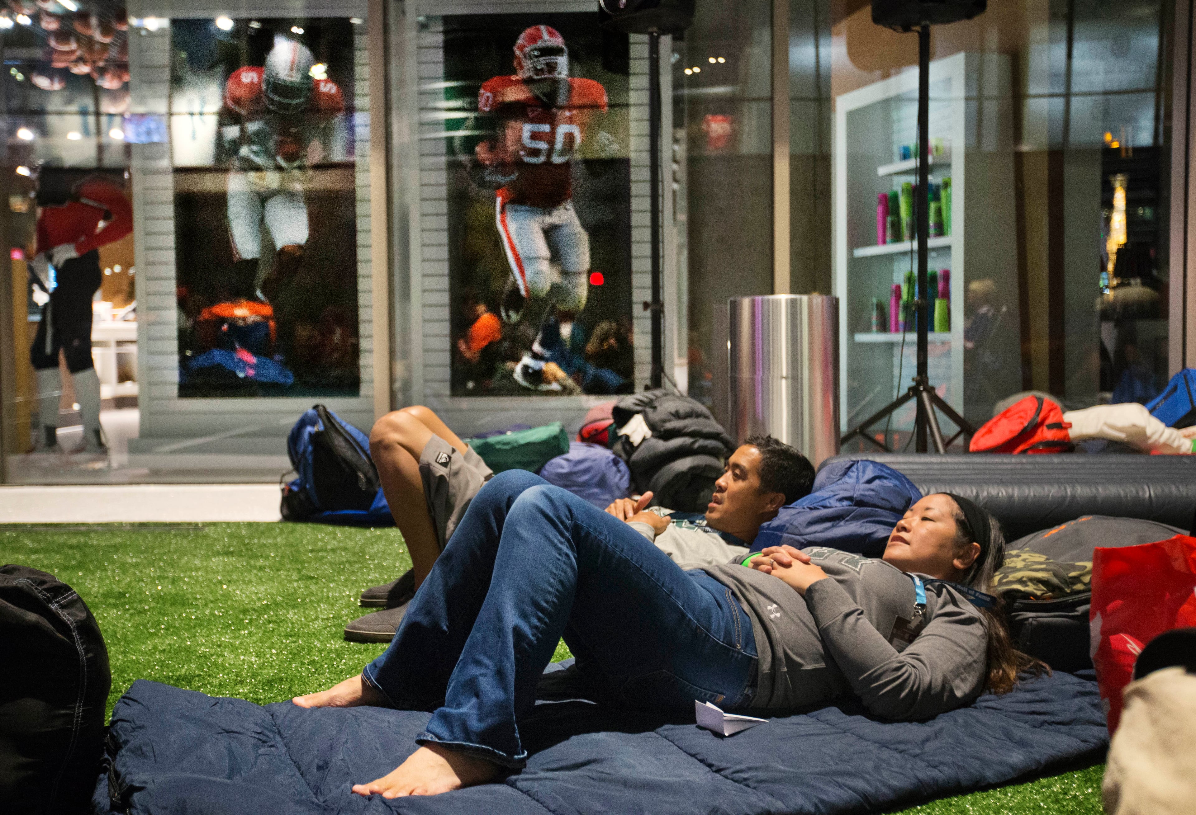 Kylie Luke, left, and Sheri Luke, both of Honolulu, watch the movie "Rudy" during a sleepover in the College Football Hall of Fame, Wednesday, Aug. 13, 2014, in Atlanta. One hundred contest winners who wrote an essay detailing their love of college football were selected to stay with a guest overnight in Atlanta's College Football Hall of Fame before its grand opening and win a year's supply of Chick-fil-A. The crowd of 200 who came from as far away as Hawaii were among the first to experience the College Football Hall of Fame and Chick-fil-A Fan experience before it opens to the public on Aug. 23. After touring the exhibits guest were served dinner on the football field before pitching their tents on the turf and settling in for the night as college football themed movies such as "Rudy" were played on the jumbotron. The hall was previously located in South Bend, Indiana, but was plagued by poor attendance. (AP Photo/David Goldman)
