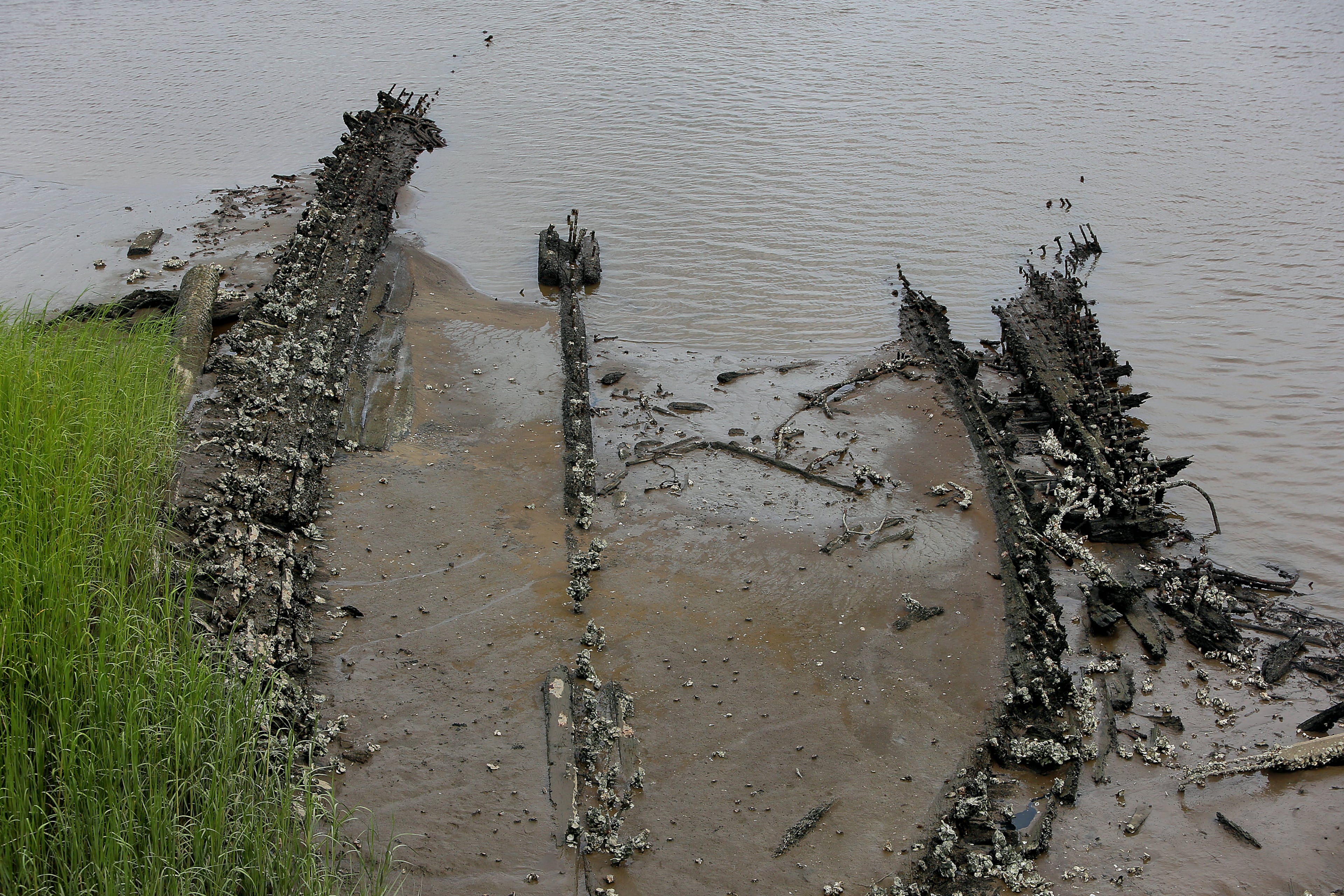 The 120-foot hull of the Back River shipwreck, a post-Reconstruction era double-mast schooner that probably carried timber, rice or salt from Savannah, becomes exposed at low tide on the muddy bank beside the Georgia side of the U.S. 17 bridge at Hutchinson Island. Owners routinely ran their vessels aground, burned them to the waterline and salvaged metal fittings and other items on the little-used river. Georgia's rich maritime history envelopes pirates and Confederate blockade runners and the remnants of perhaps hundreds of other half-buried shipwrecks.