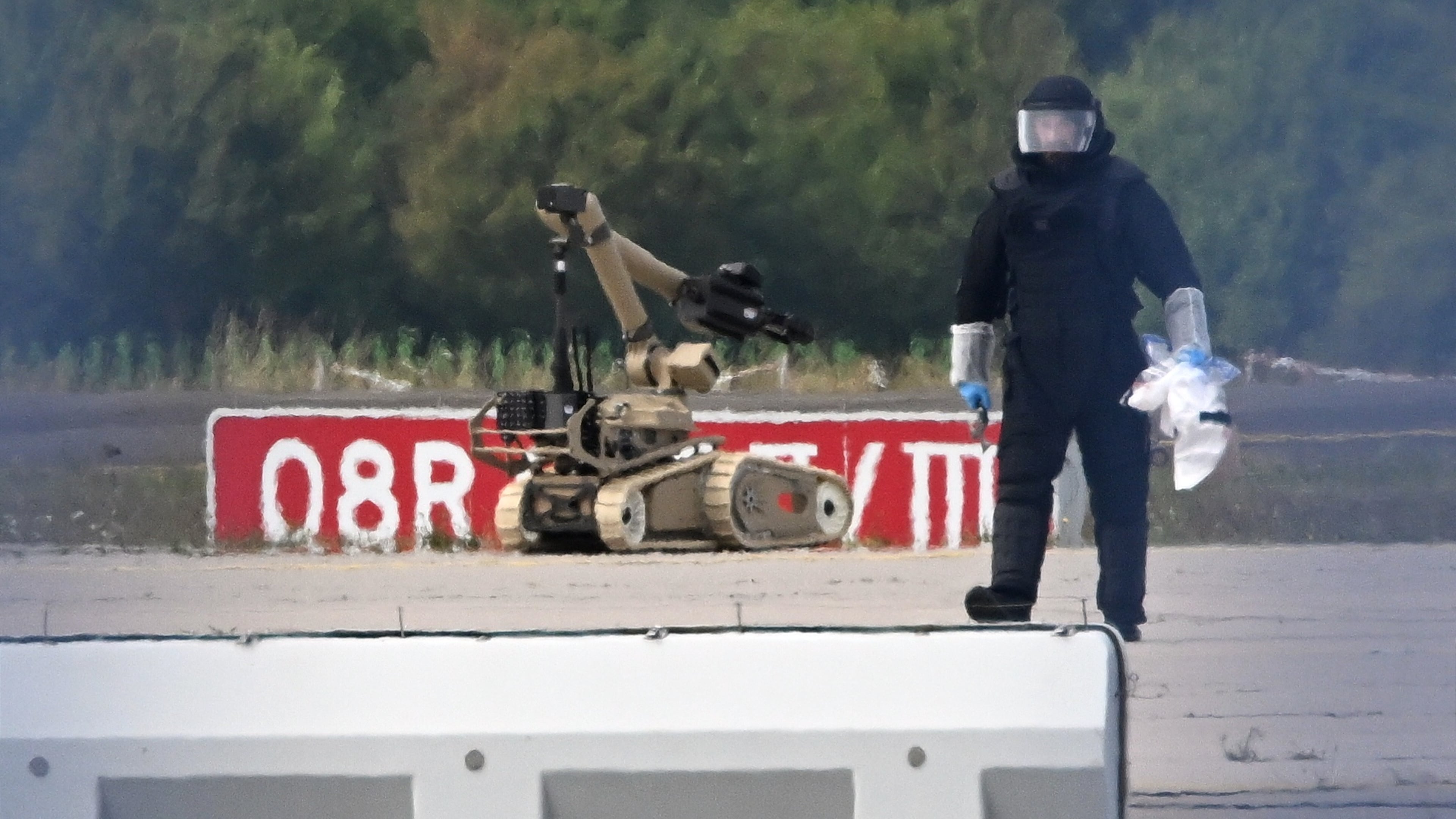 A forensic technician works alongside a bomb-disposal robot near a Ukrainian aircraft at Leipzig/Halle Airport, where a drone with an explosive device was found and a detonator was removed from the object, in Schkeuditz, Germany, Wednesday Aug. 5, 2026. (Hendrik Schmidt/dpa via AP)