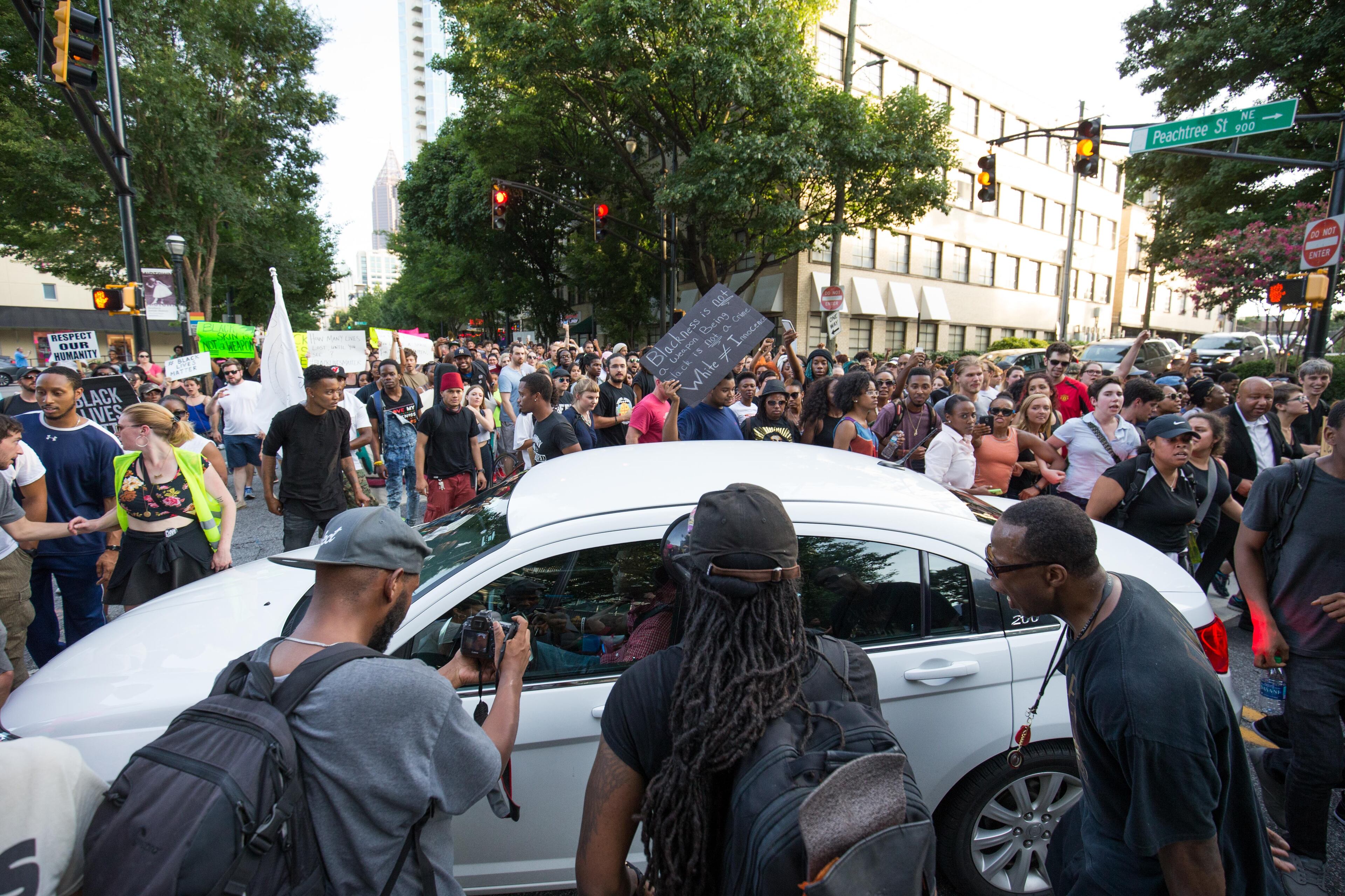 Demonstrators surround a car as they march down Peachtree Street to Piedmont Park, Thursday, July 7, 2016, in Atlanta. They were responding to the death of 37-year-old Alton Sterling, who was killed by Baton Rouge police outside of a convenience store where he was selling CDs and Philando Castile, who was shot and killed when Minnesota police stopped him for a traffic violation on Wednesday evening. BRANDEN CAMP/SPECIAL