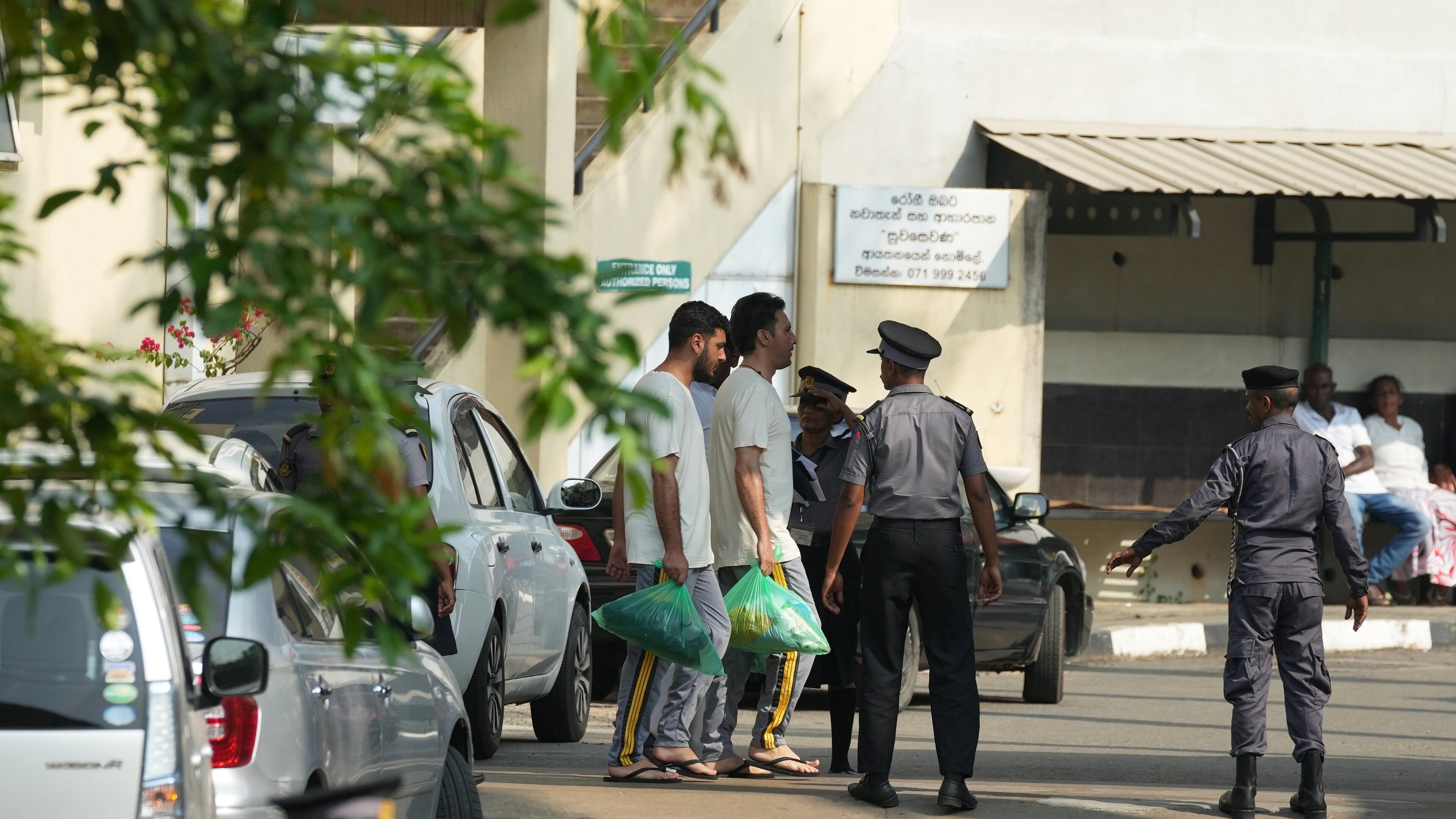 Two Iranian sailors, carrying green bags, who were rescued from IRIS Dena warship by Sri Lanka's navy are escorted to a Judicial Medical Officer from the National Hospital, in Galle, Sri Lanka, Thursday, March 5, 2026. (AP Photo/Eranga Jayawardena)