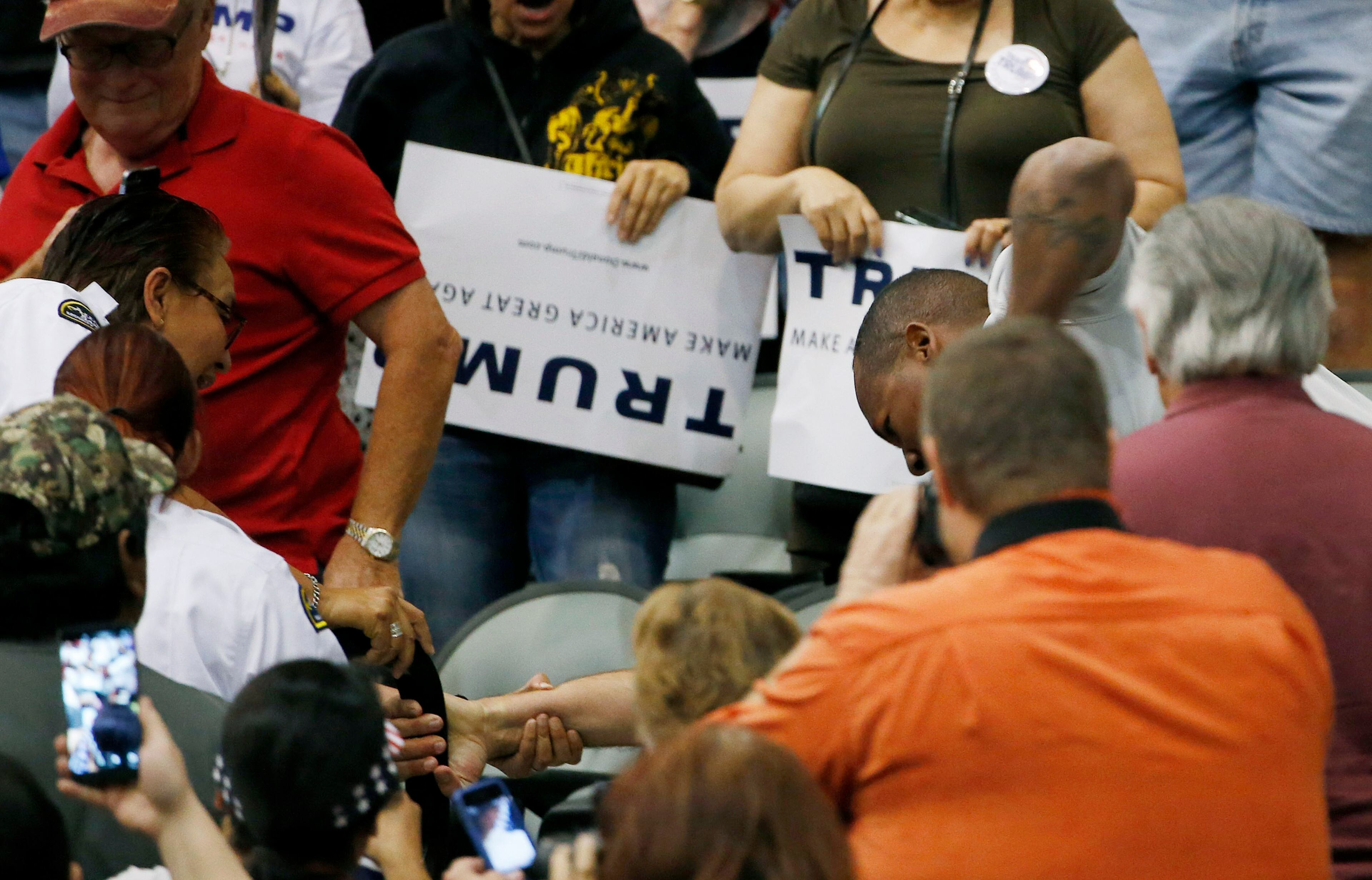 Members of security, left, try to break up a scuffle between an anti-Donald Trump protester, out of picture, and another person, second from right, as the Republican presidential candidate was speaking during a campaign rally Saturday, March 19, 2016, in Tucson, Ariz. (AP Photo/Ross D. Franklin)