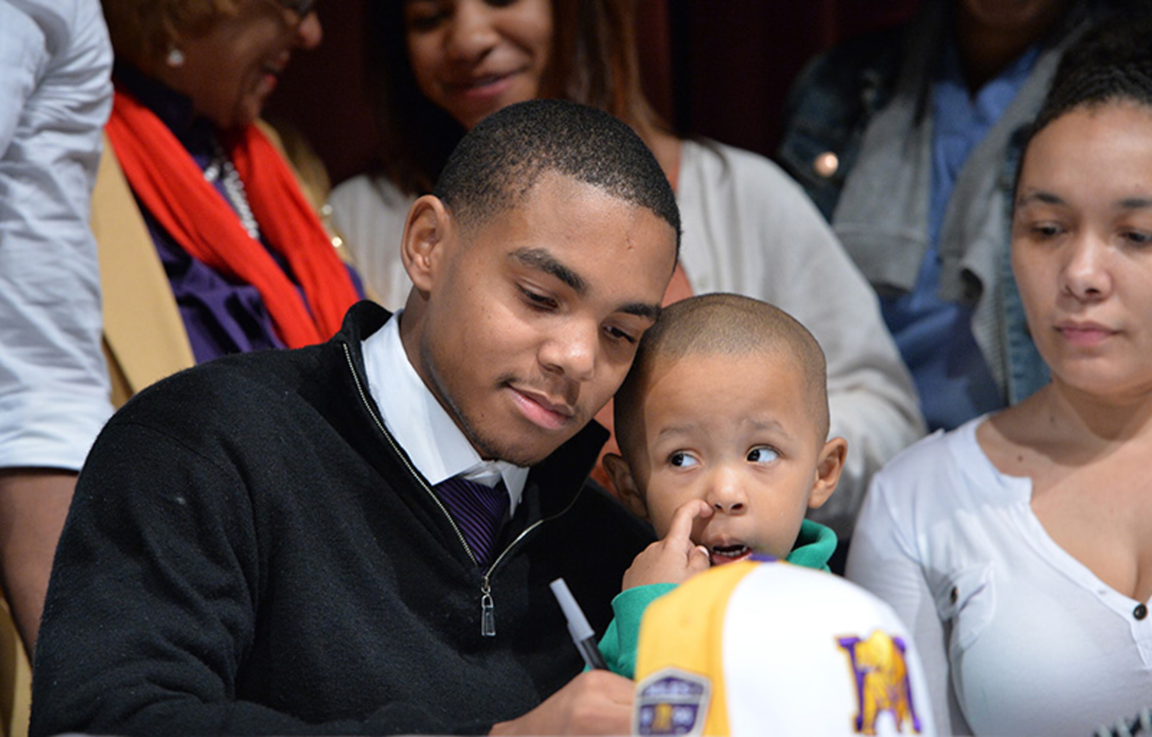 Jalen Pearson holds his 1-year-old brother, Grant, as he signs his letter of intent to Miles College during signing day at Tucker High School.