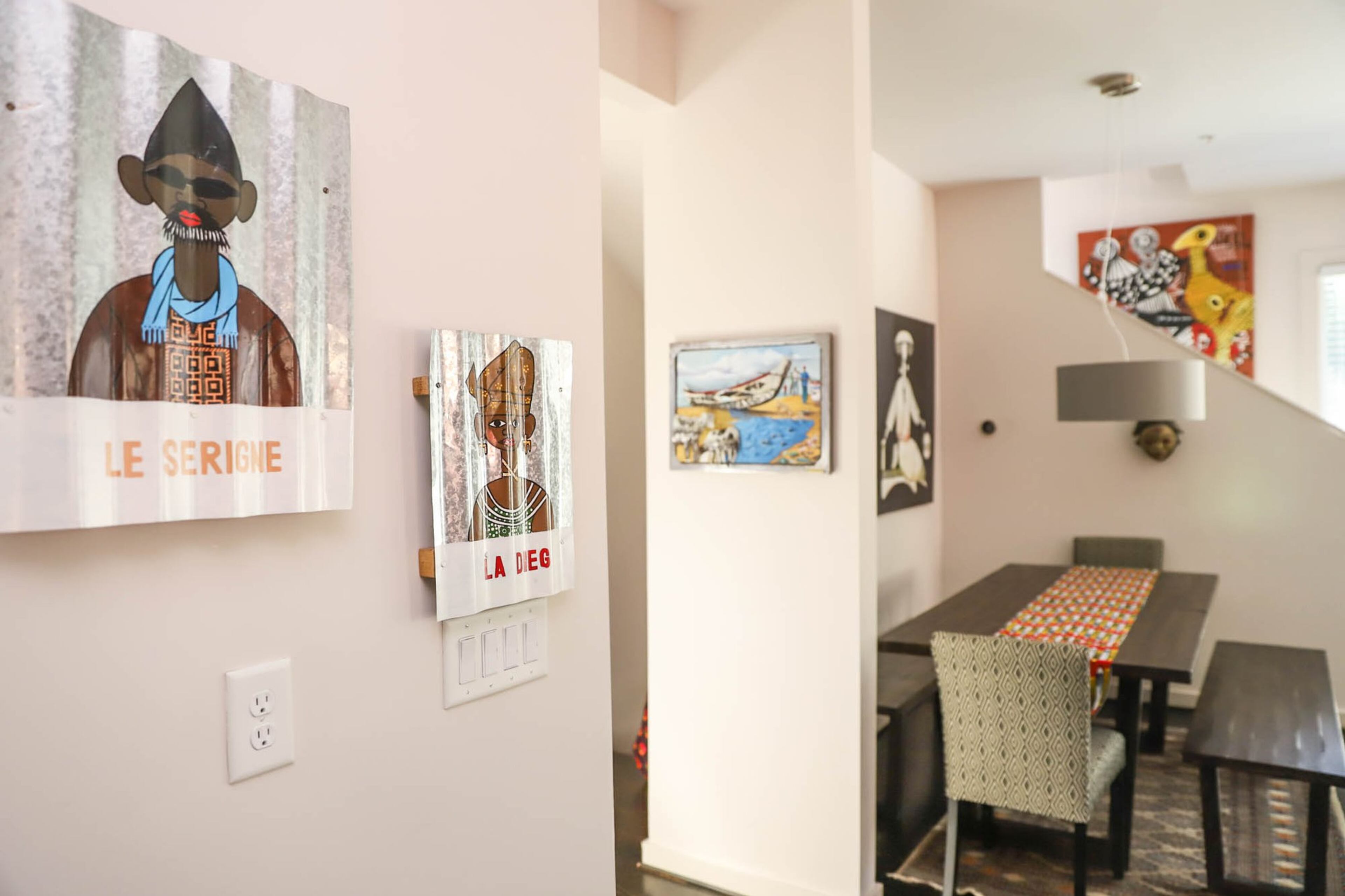 Street art on corrugated iron from Senegal hangs in the kitchen of Anja and Jumbe Sebunya's Old Fourth Ward home. "I like the idea of how people innovatively use recycled product," said Anja. "The paintings are of very average people that would would come across as you walk around Dakar." The couple acquired a collection of African art in the 25 years of living in different countries around the continent. Text by Shannon Dominy. Photo by Reynolds Rogers.