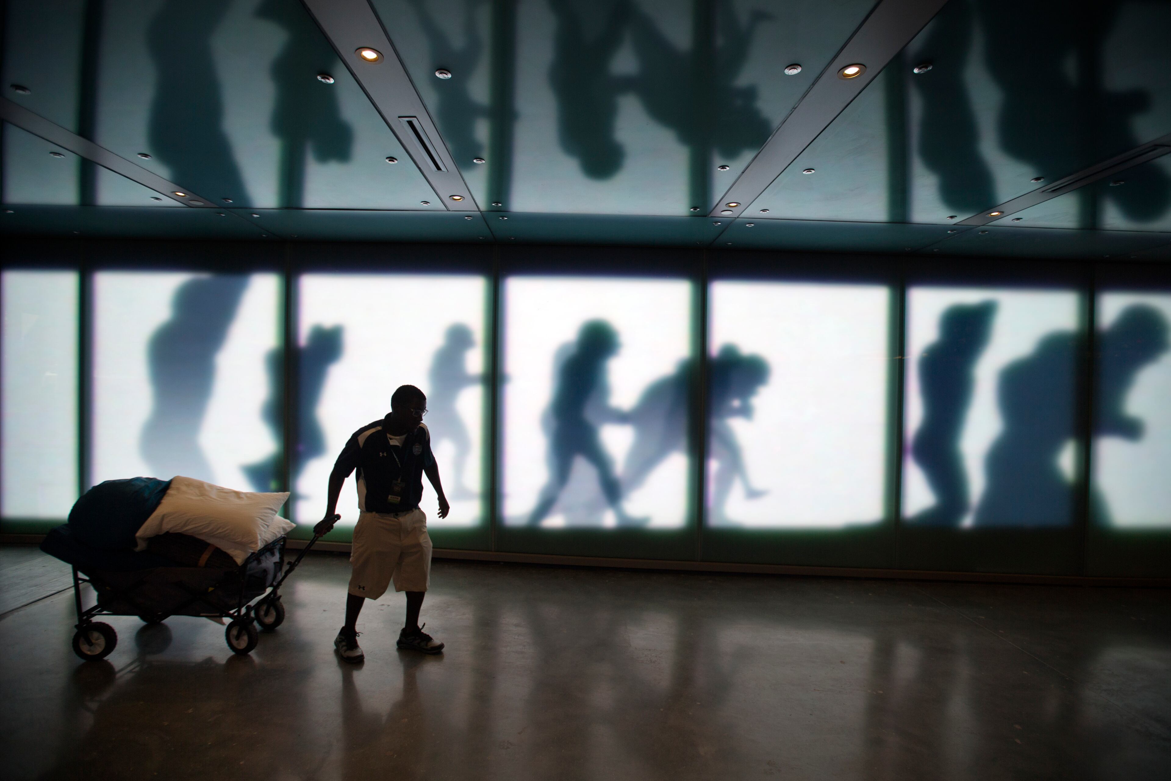 AP10ThingsToSee - Fan ambassador Justin Ikusebiala wheels a cart stocked with pillows and blankets belonging to a guest who just arrived to spend the night in the College Football Hall of Fame before its grand opening, Wednesday, Aug. 13, 2014, in Atlanta. (AP Photo/David Goldman)