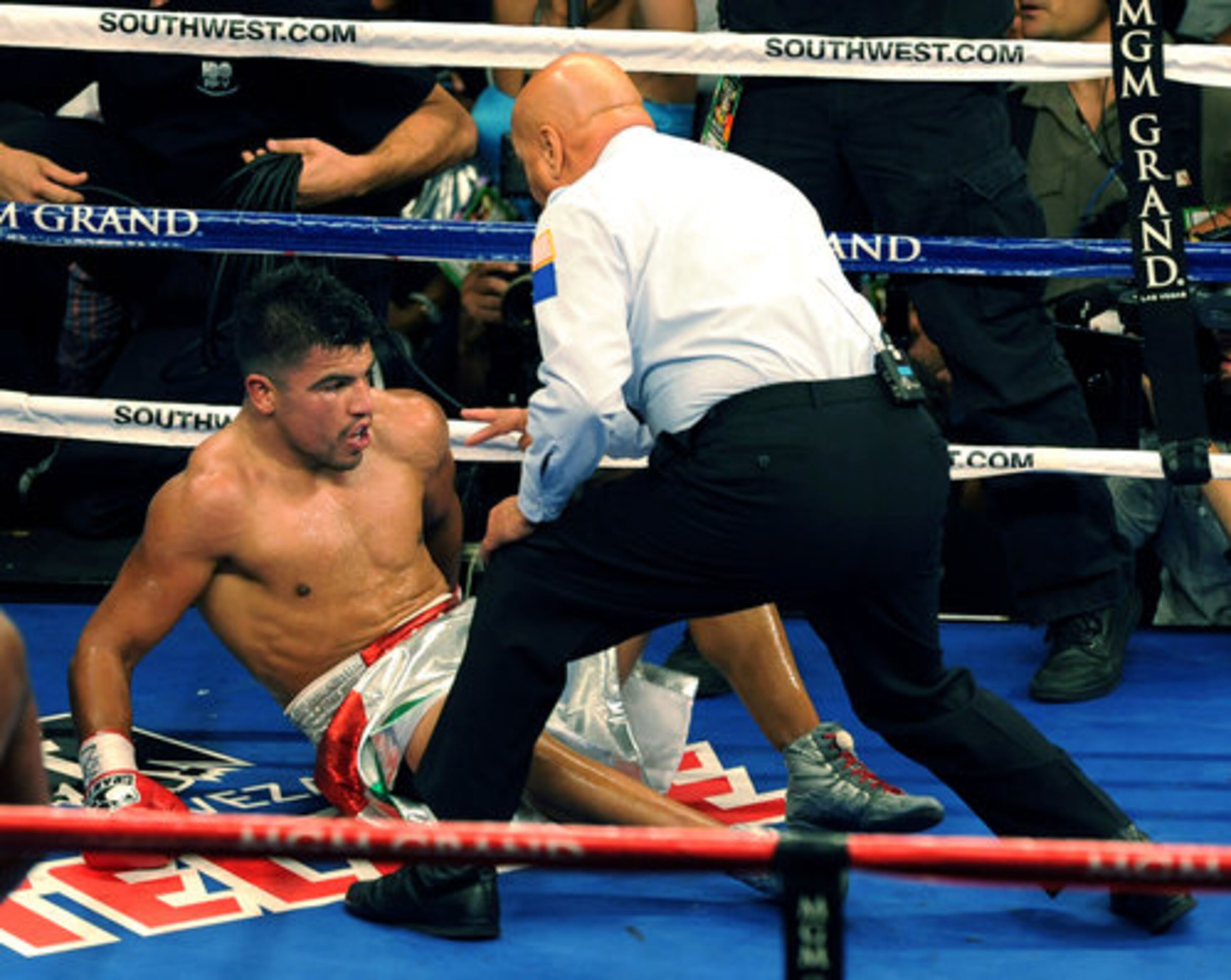 Referee Joe Cortez checks on Victor Ortiz during the WBC Welterweight boxing bout, who was stunned by the knockout punch that Ortiz wasn't expecting, following a stoppage in the bout due to Ortiz headbutting Mayweather.
